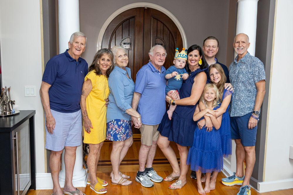 A multi-generational family poses together in coordinated blue and yellow outfits for a group photo.