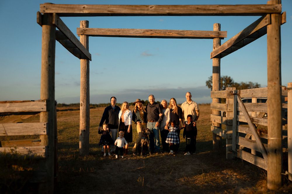 Group photo taken at sunset through a rustic wooden gate frame overlooking the ocean.