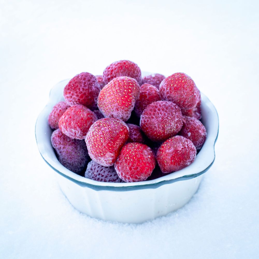 Fresh frozen raspberries in a white ceramic bowl against a light background located in Alanteen Tila, Paimio, Finland.