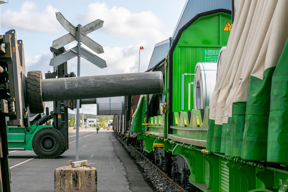 Green industrial train cars and loading equipment at a railway crossing.