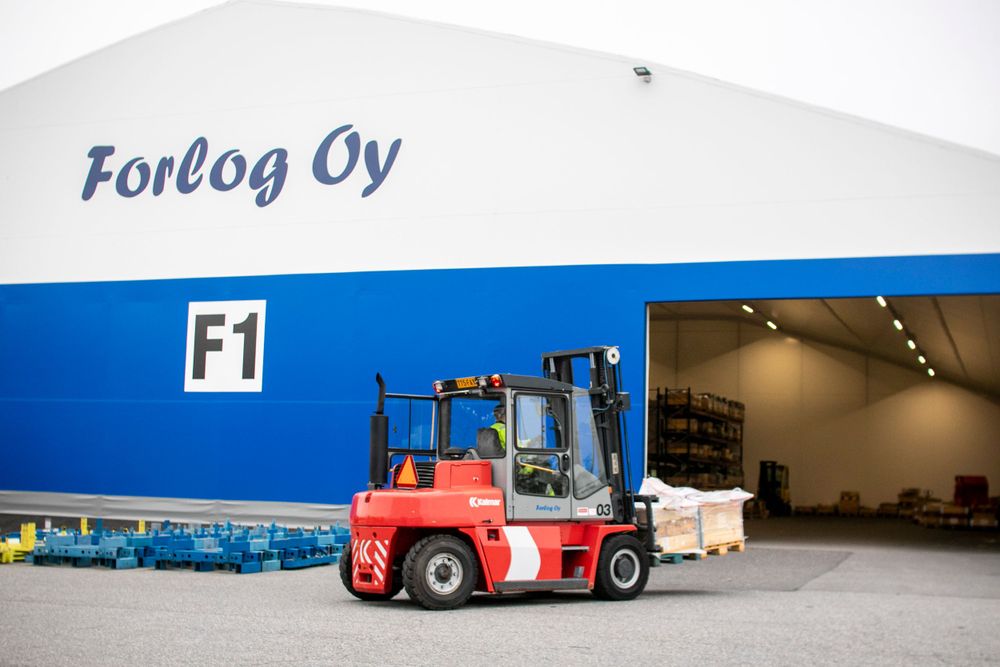 Red forklift parked outside a blue and white industrial warehouse building.