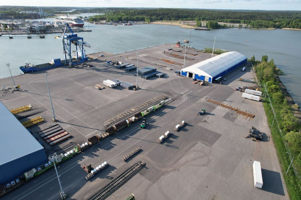 Aerial view of an industrial port facility with shipping containers and loading equipment.
