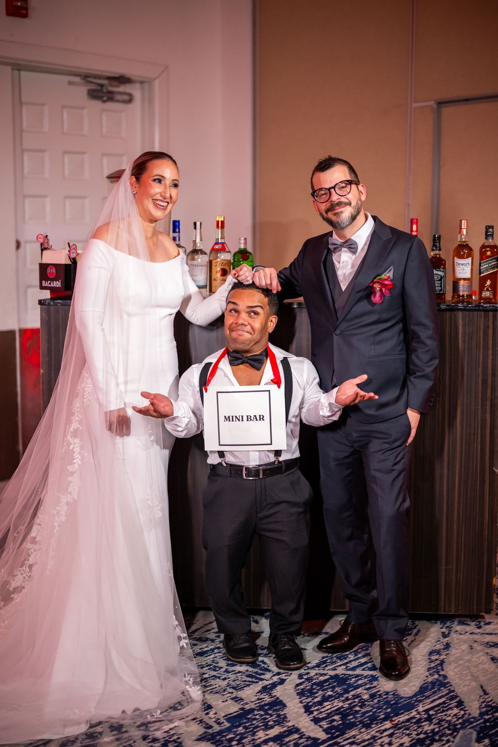Celebratory moment captured at wedding reception with attendants near bar area.