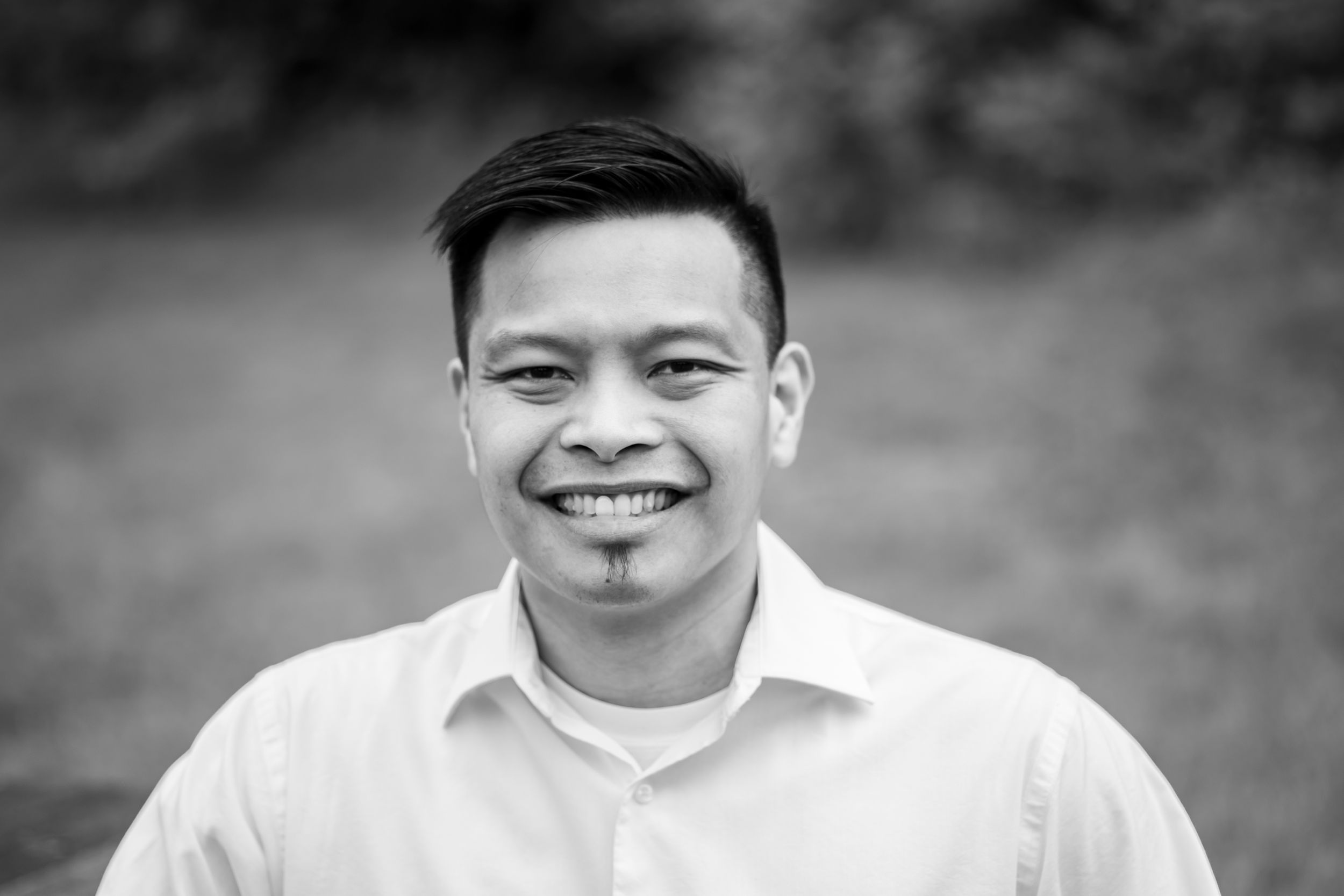 Black and white portrait of person in white button down shirt with warm genuine smile.