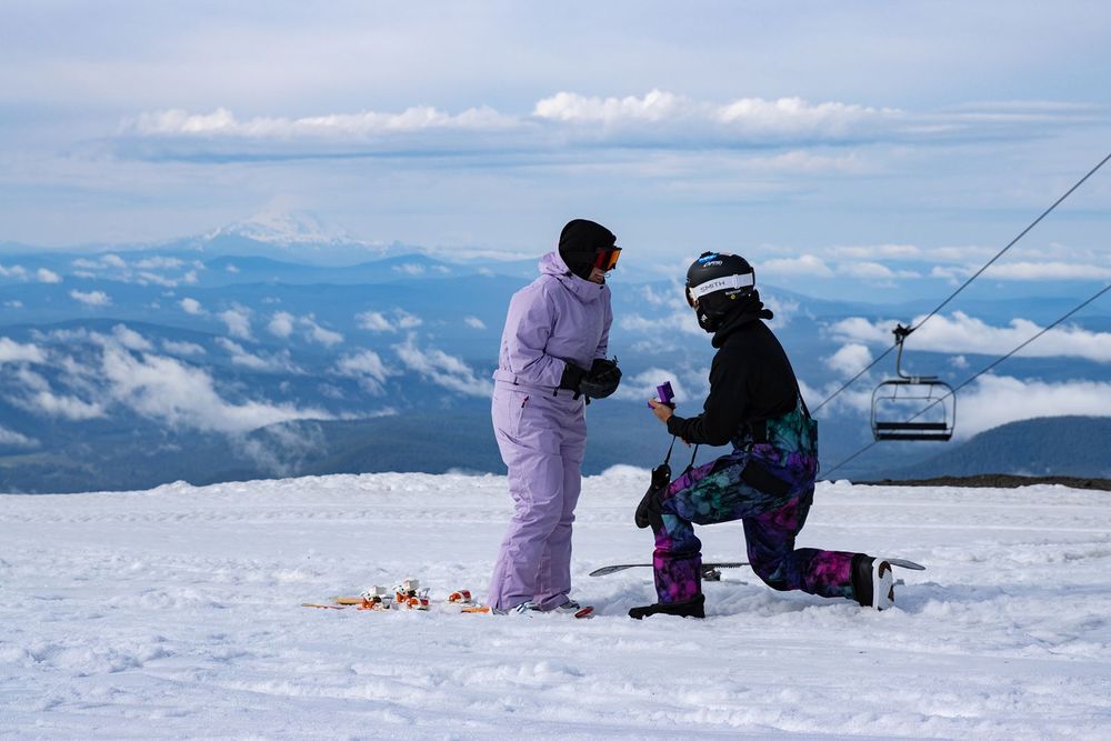 Person proposing on snowy Timberline Lodge ski slope with chairlift and clouds in background on Mt.Hood.