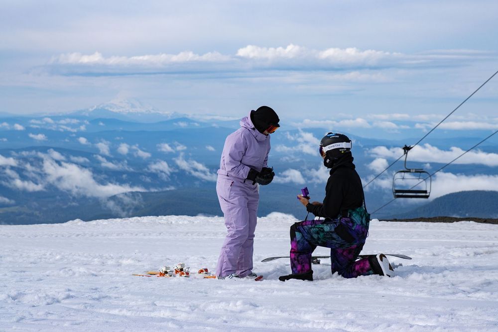 Person proposing on snowy Timberline Lodge ski slope with chairlift and clouds in background on Mt.Hood.