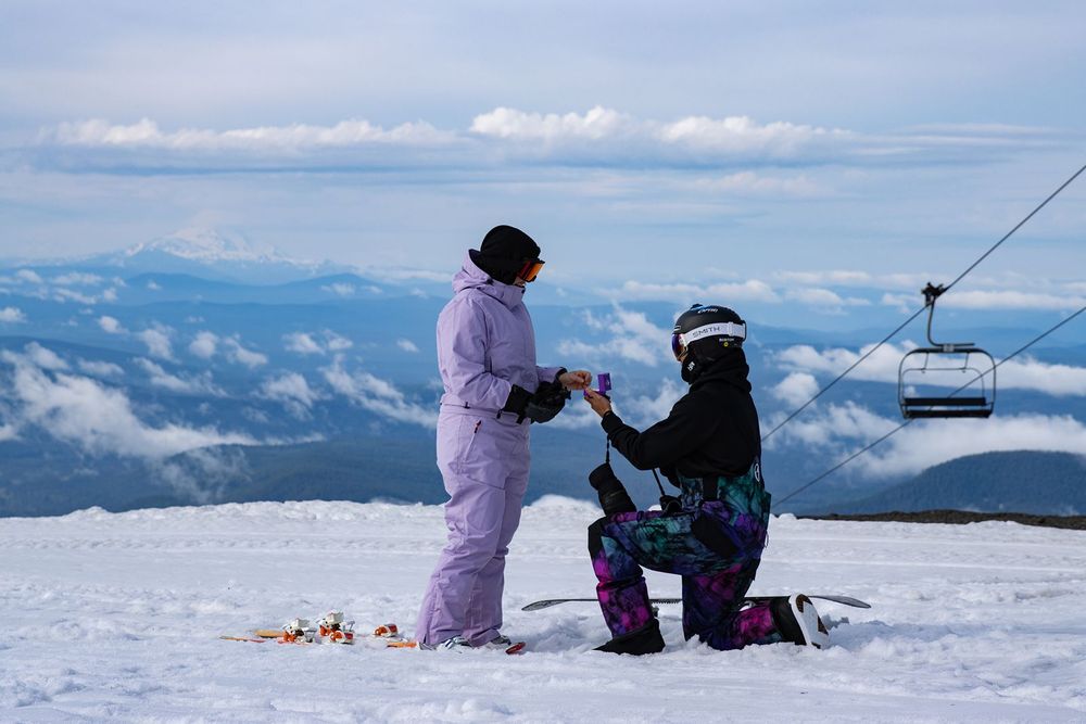 Person proposing on snowy Timberline Lodge ski slope with chairlift and clouds in background on Mt.Hood.