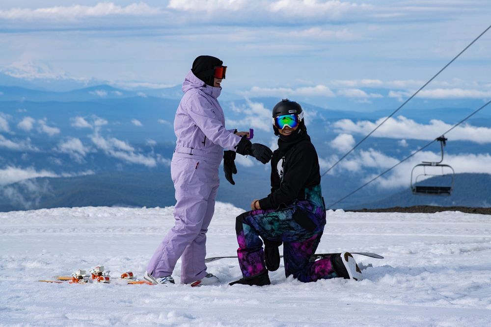 Snowboarder proposing on snowy Timberline Lodge ski slope with chairlift and clouds in background on Mt.Hood.