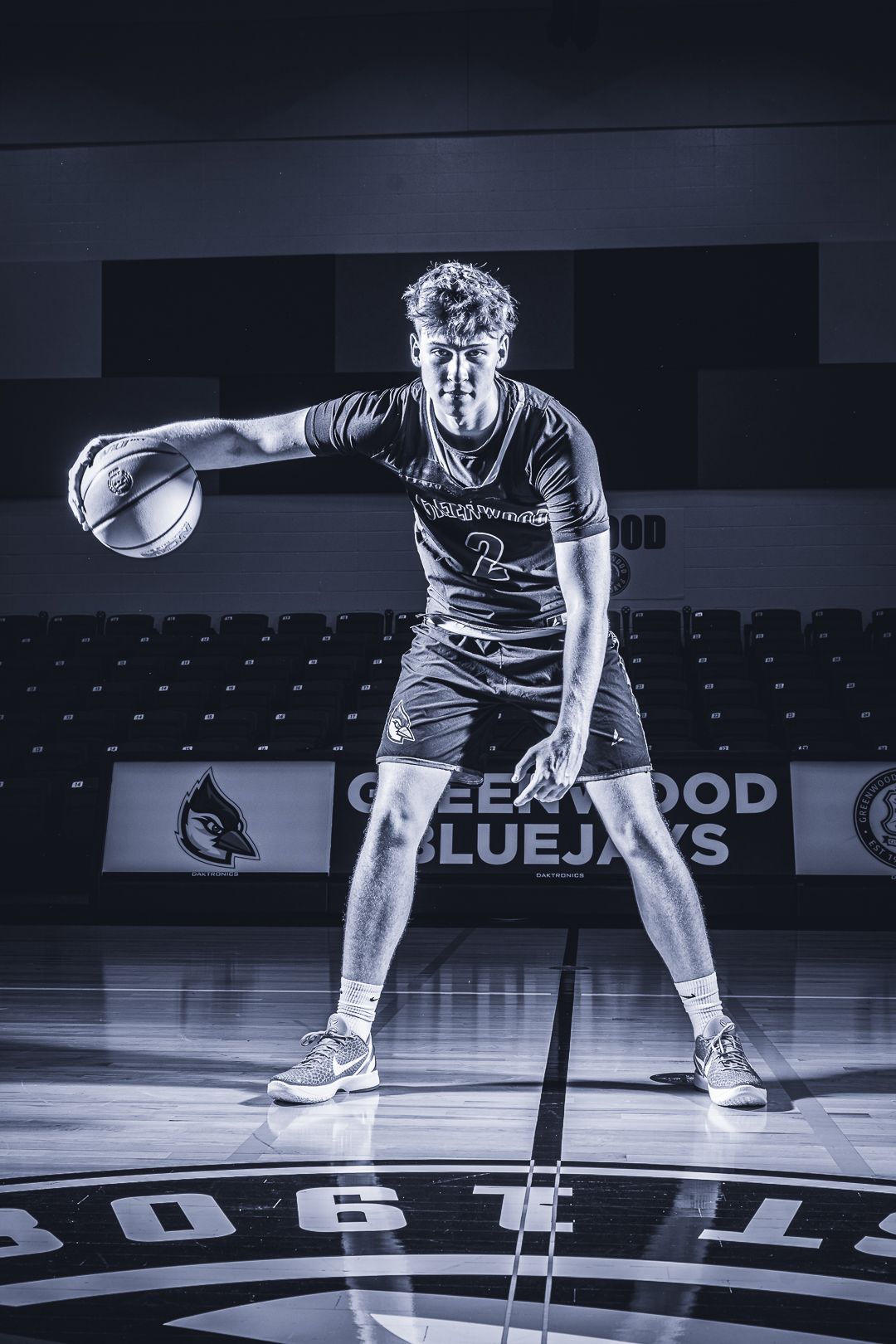 Basketball player in dramatic stance on court logo in black and white.