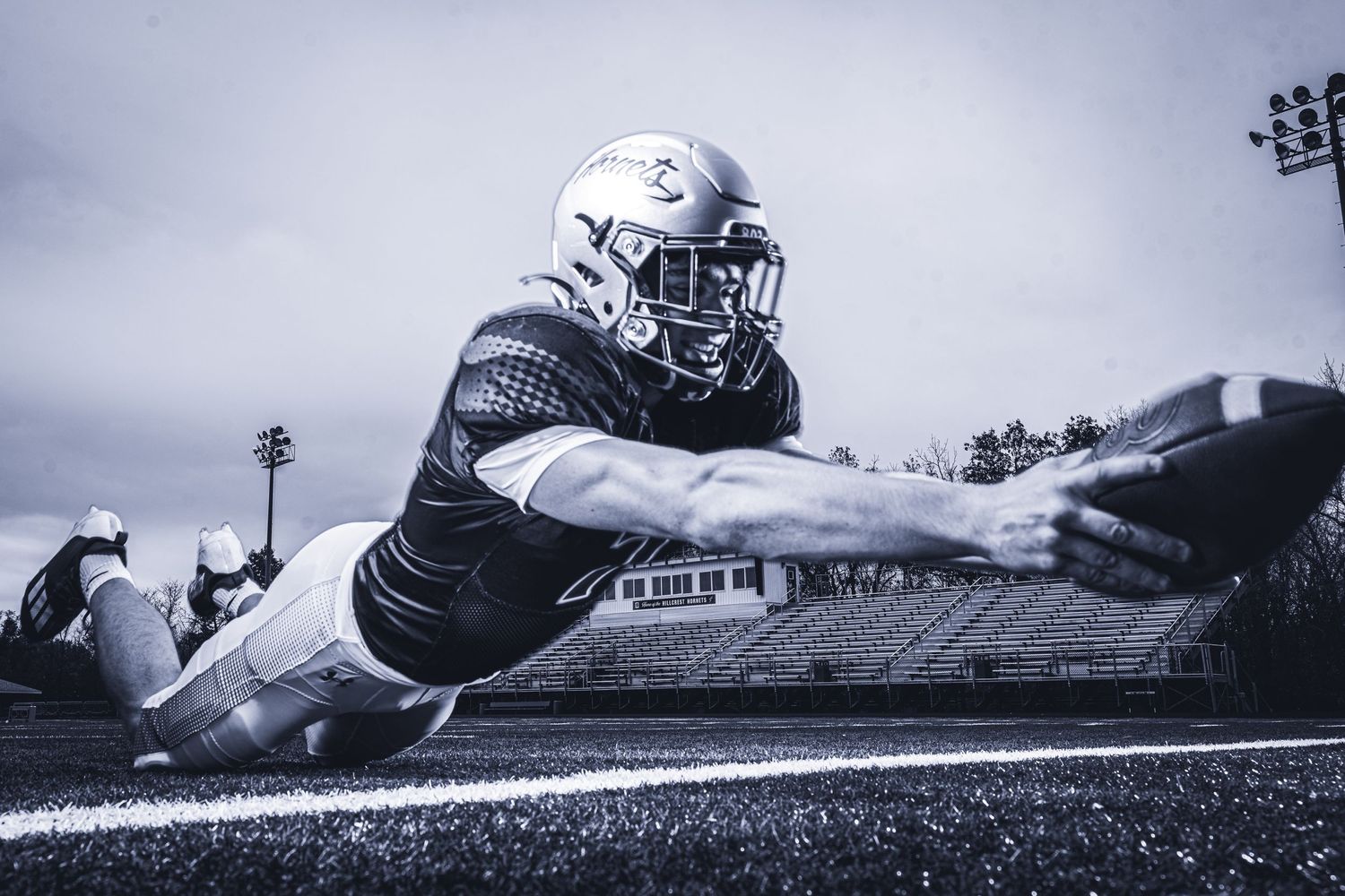 Football player diving horizontally to catch ball in dramatic black and white action shot.