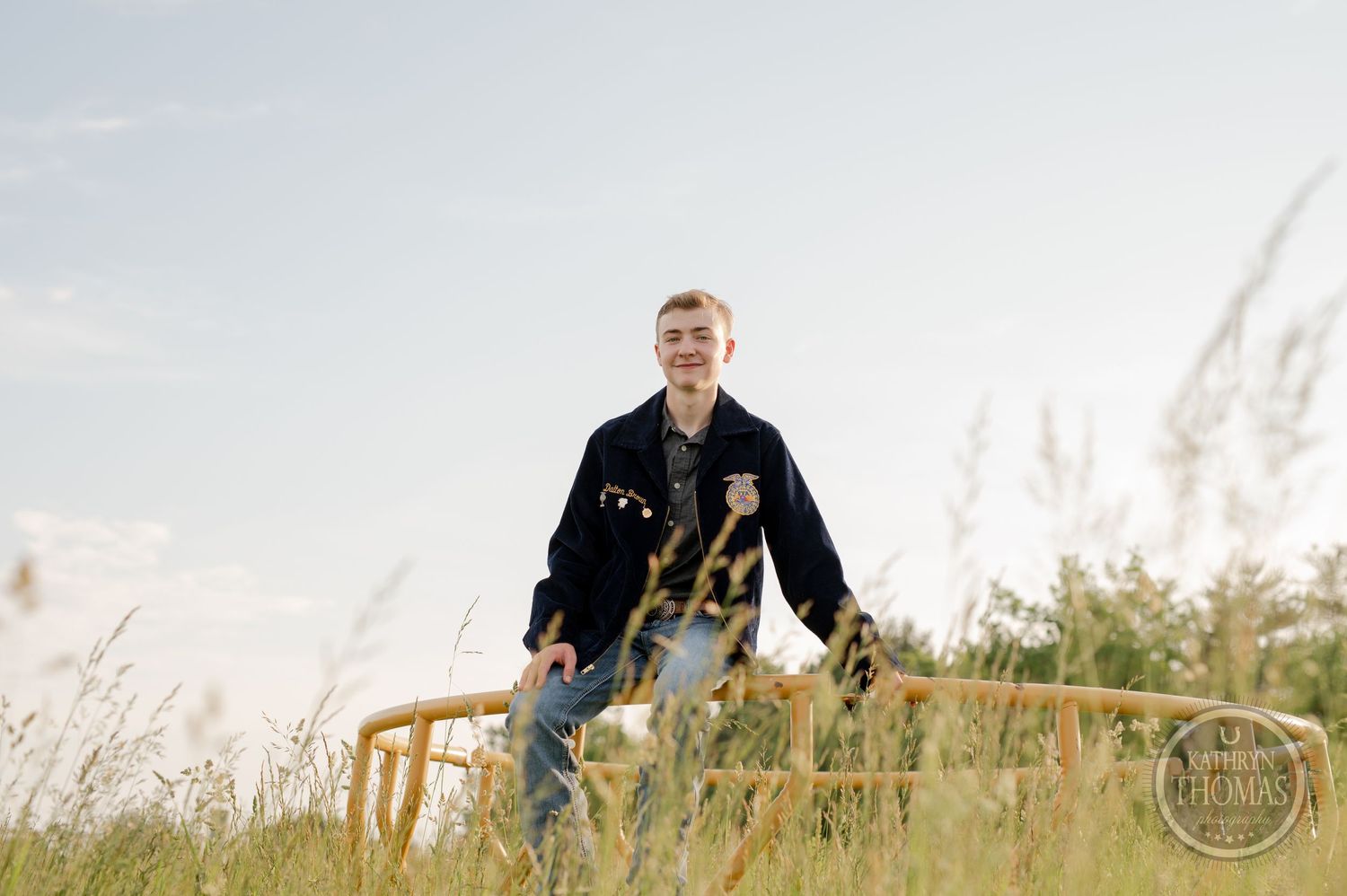 FFA member stands in golden field with yellow barrier during sunset.