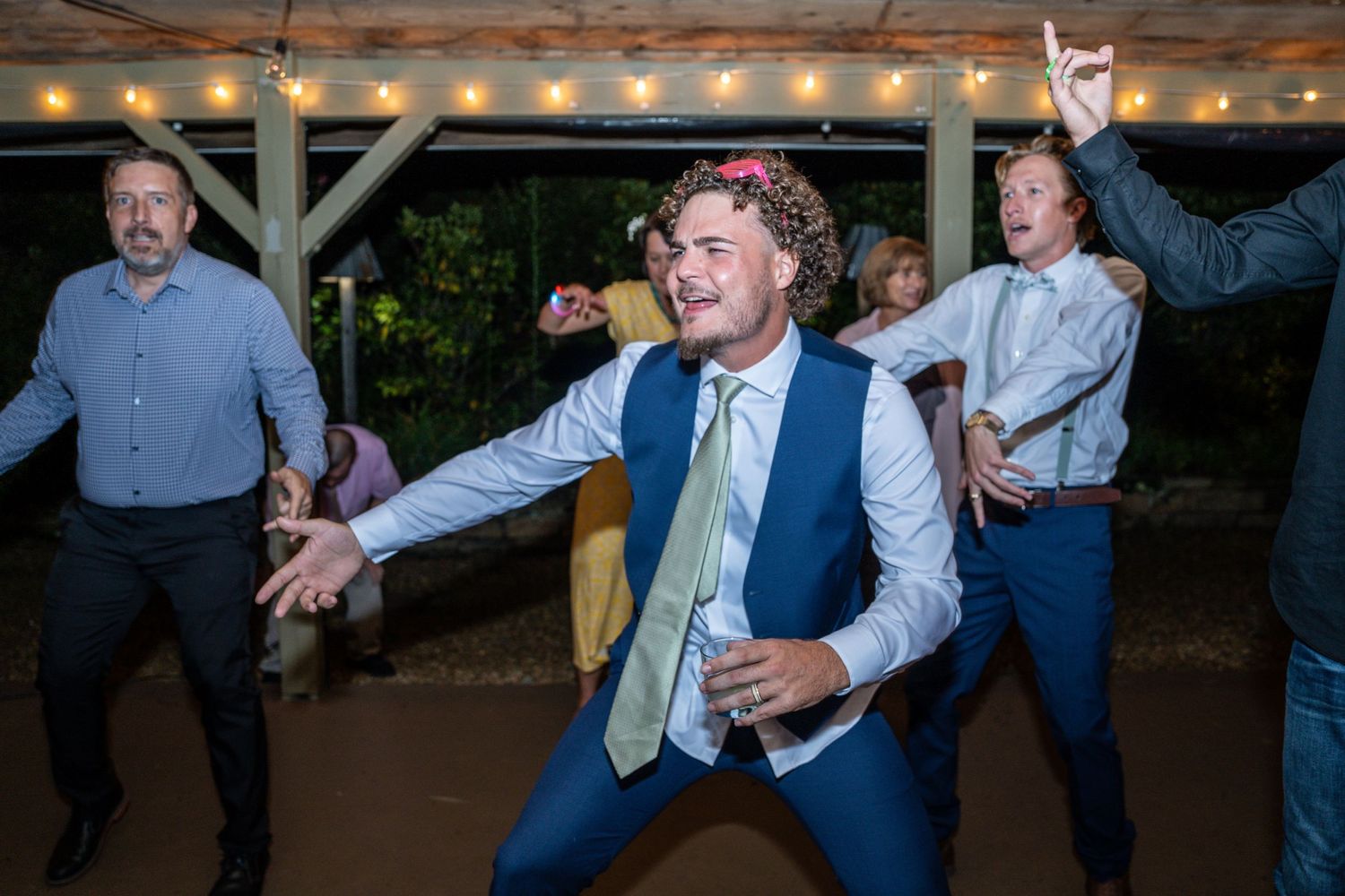 Guest showing off dance moves on the reception floor under string lights.