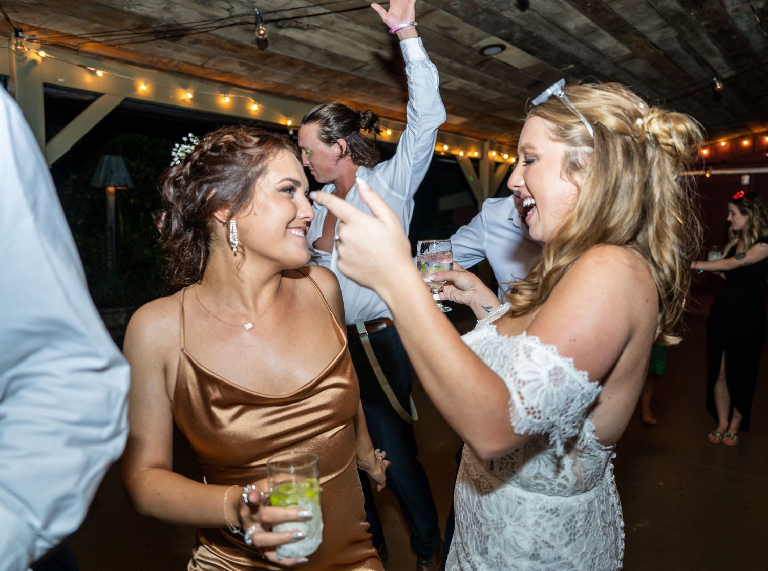 Wedding guests dancing and singing enthusiastically at an indoor reception venue.