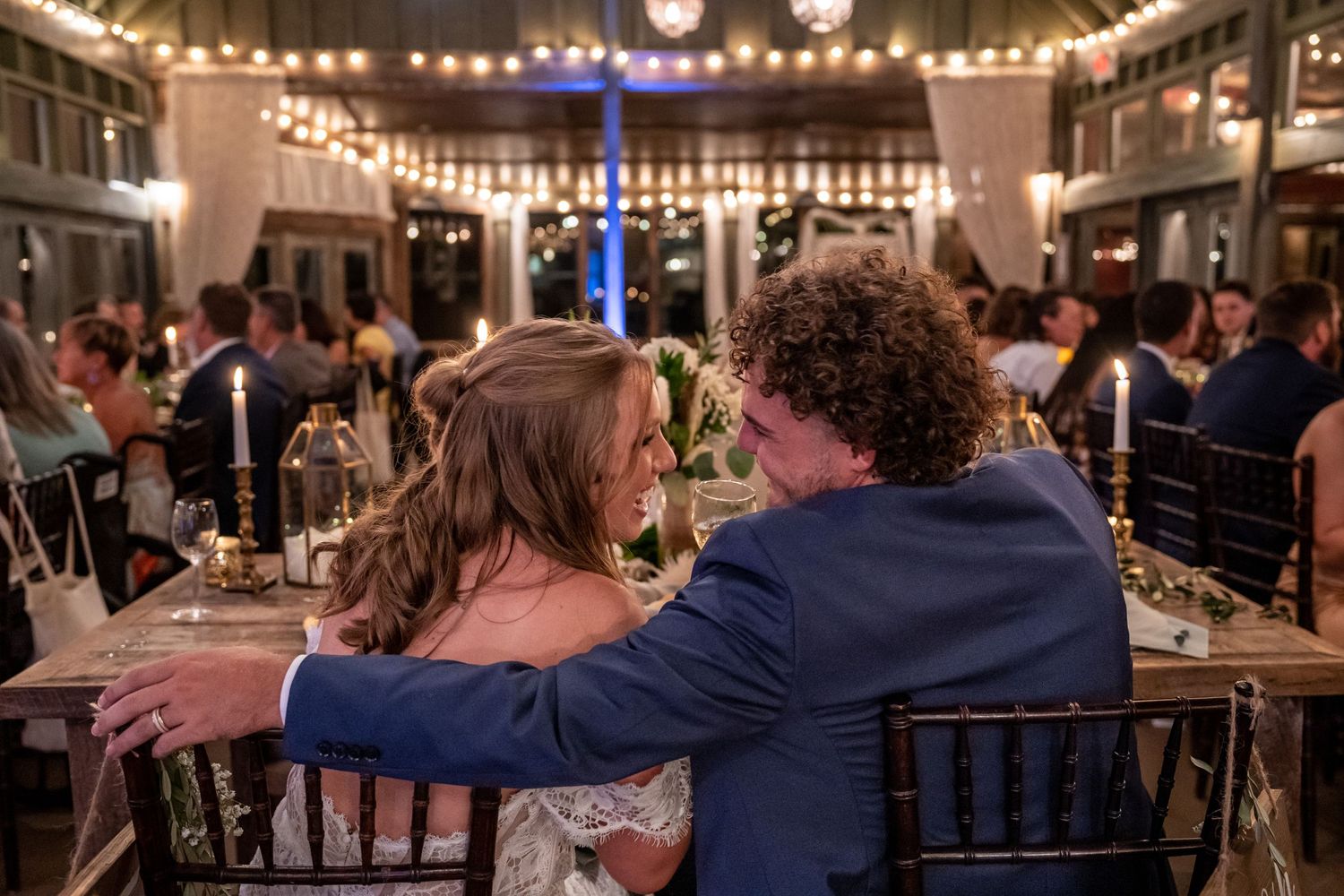 Reception scene with string lights and couple at elegant indoor venue.