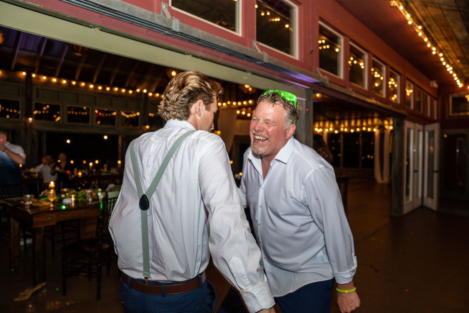 Two guests share a lighthearted moment at an indoor wedding reception.