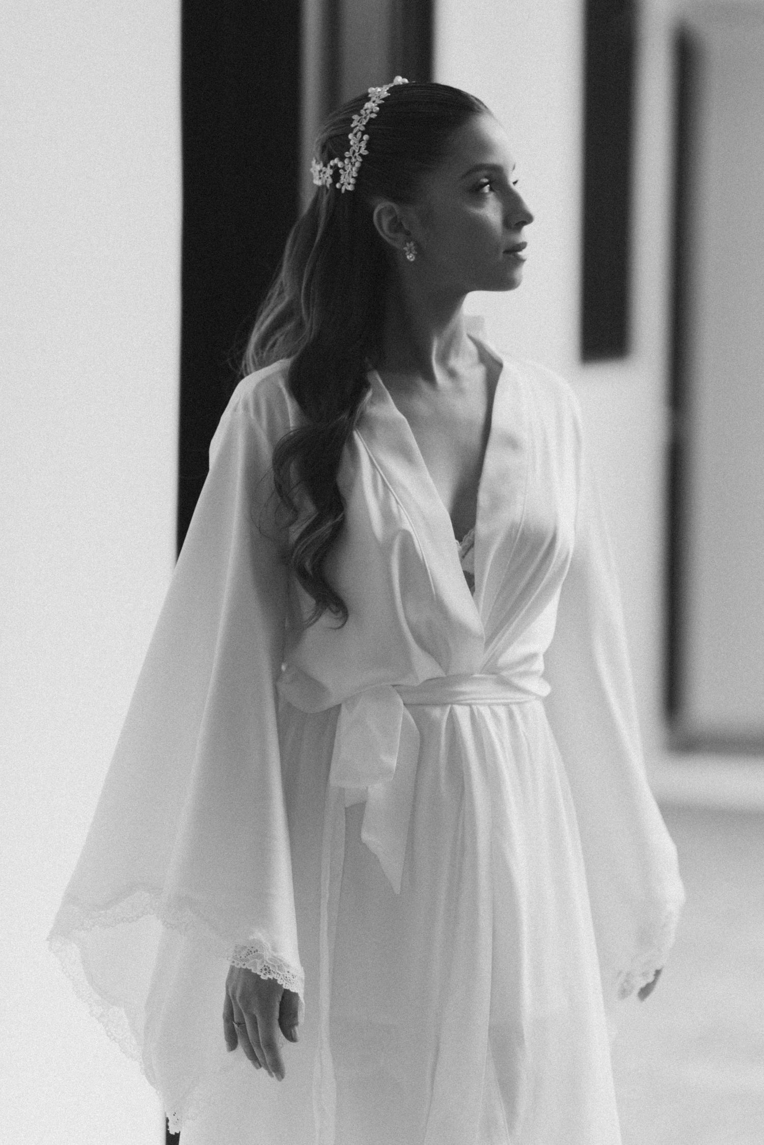Side profile of a person in white robe with delicate hair accessory.