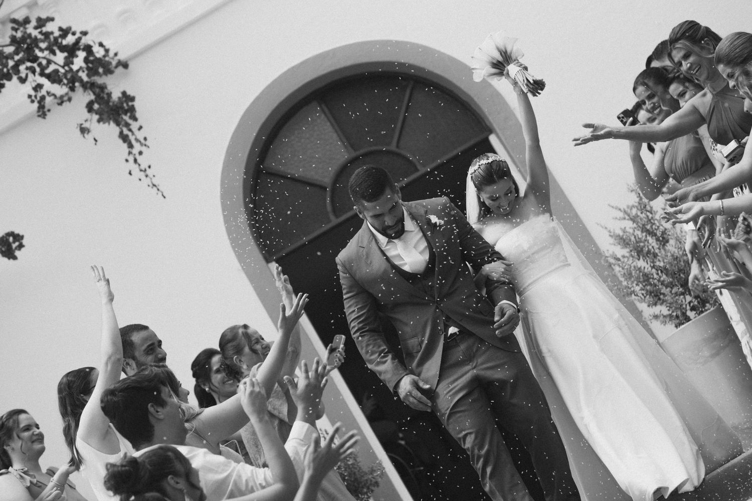 A black and white capture of wedding guests celebrating as the newlyweds exit the church.