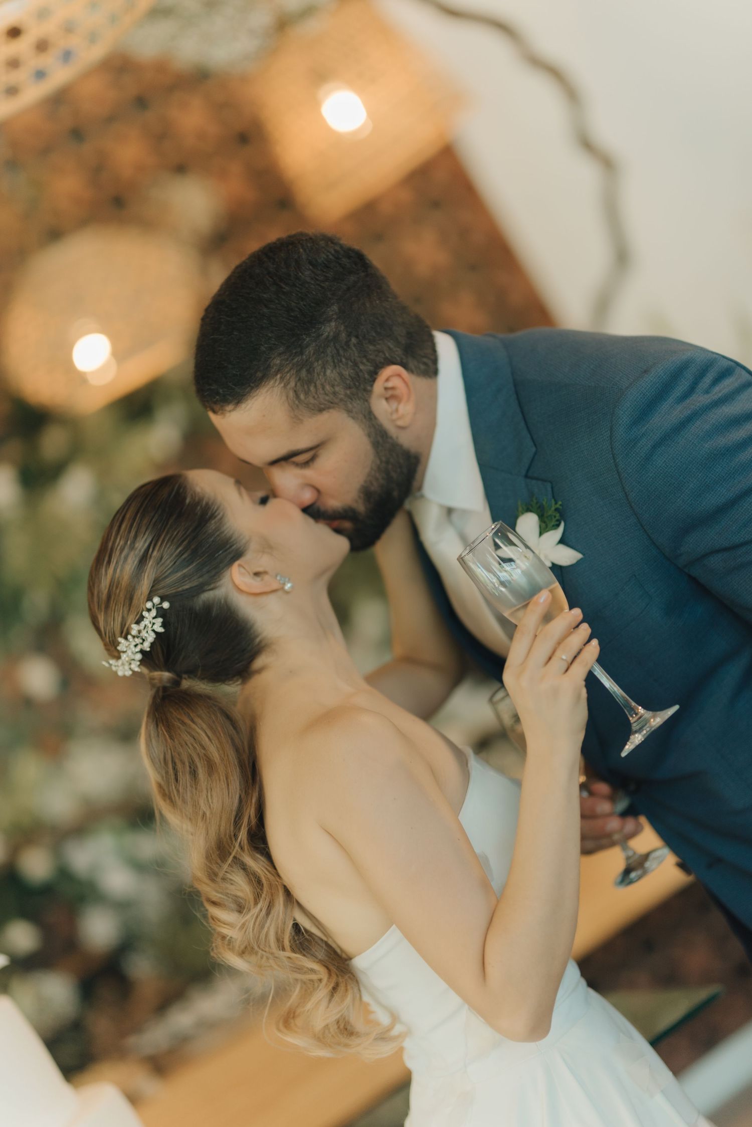 Romantic kiss between bride and groom during their wedding celebration with warm lighting.