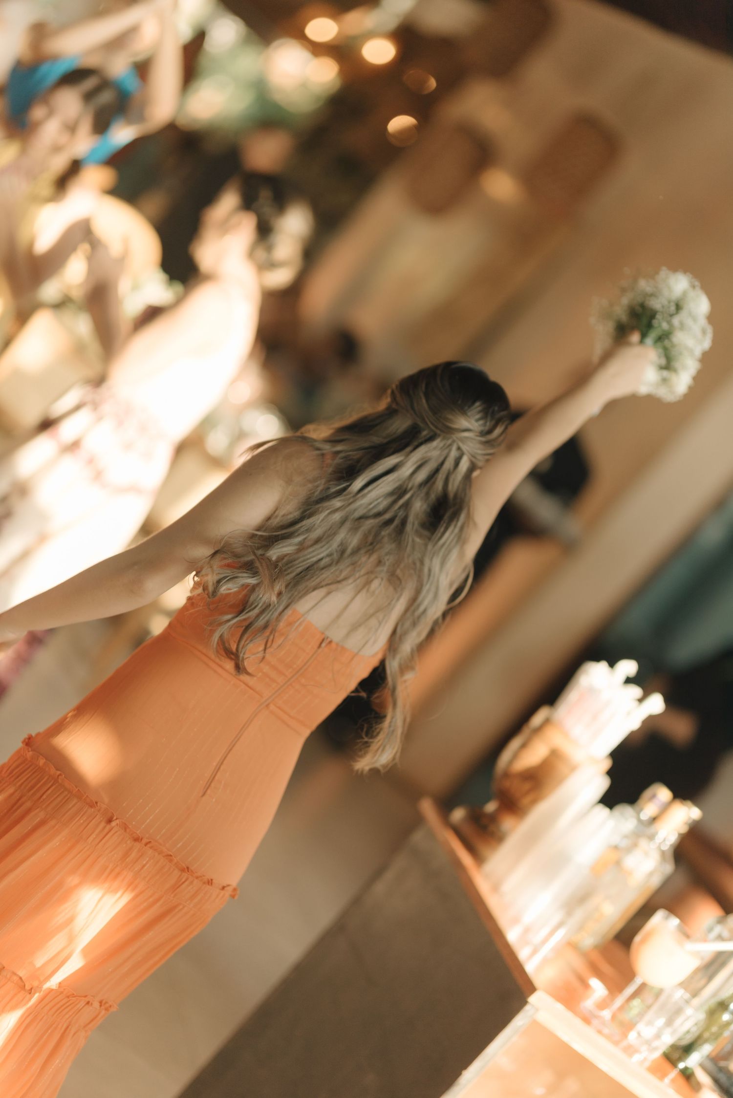 Person in peach-colored dress dancing in warm indoor lighting.