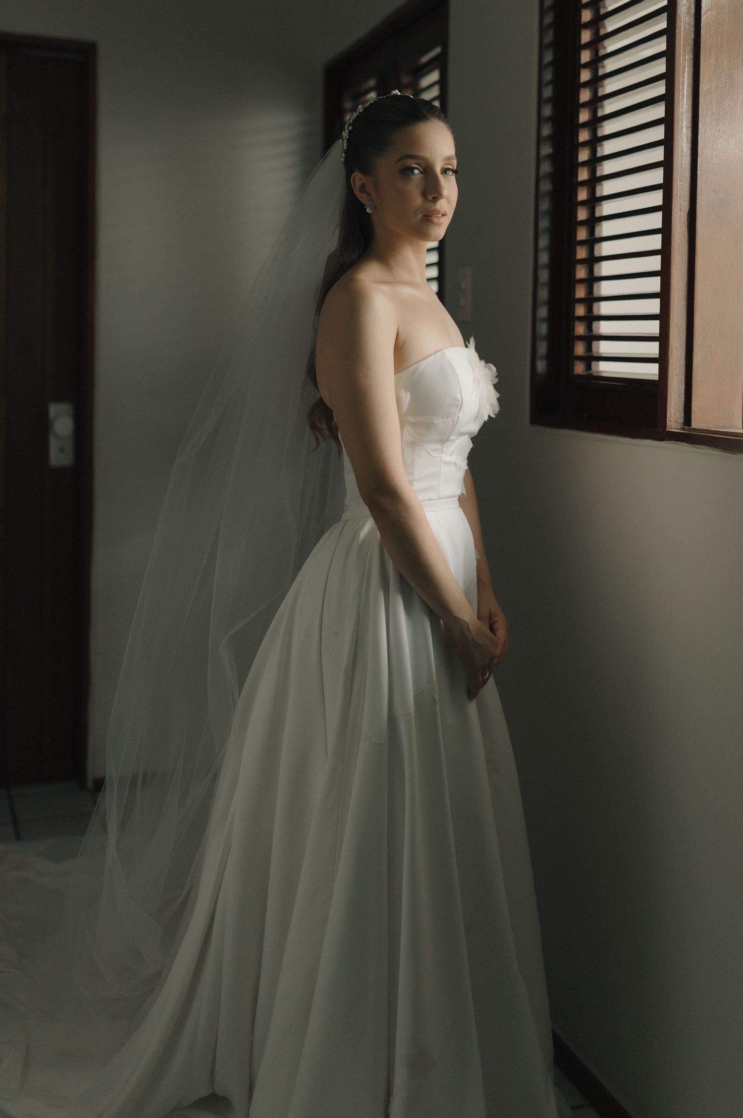 An elegant wedding dress photographed in a corridor with natural window light.