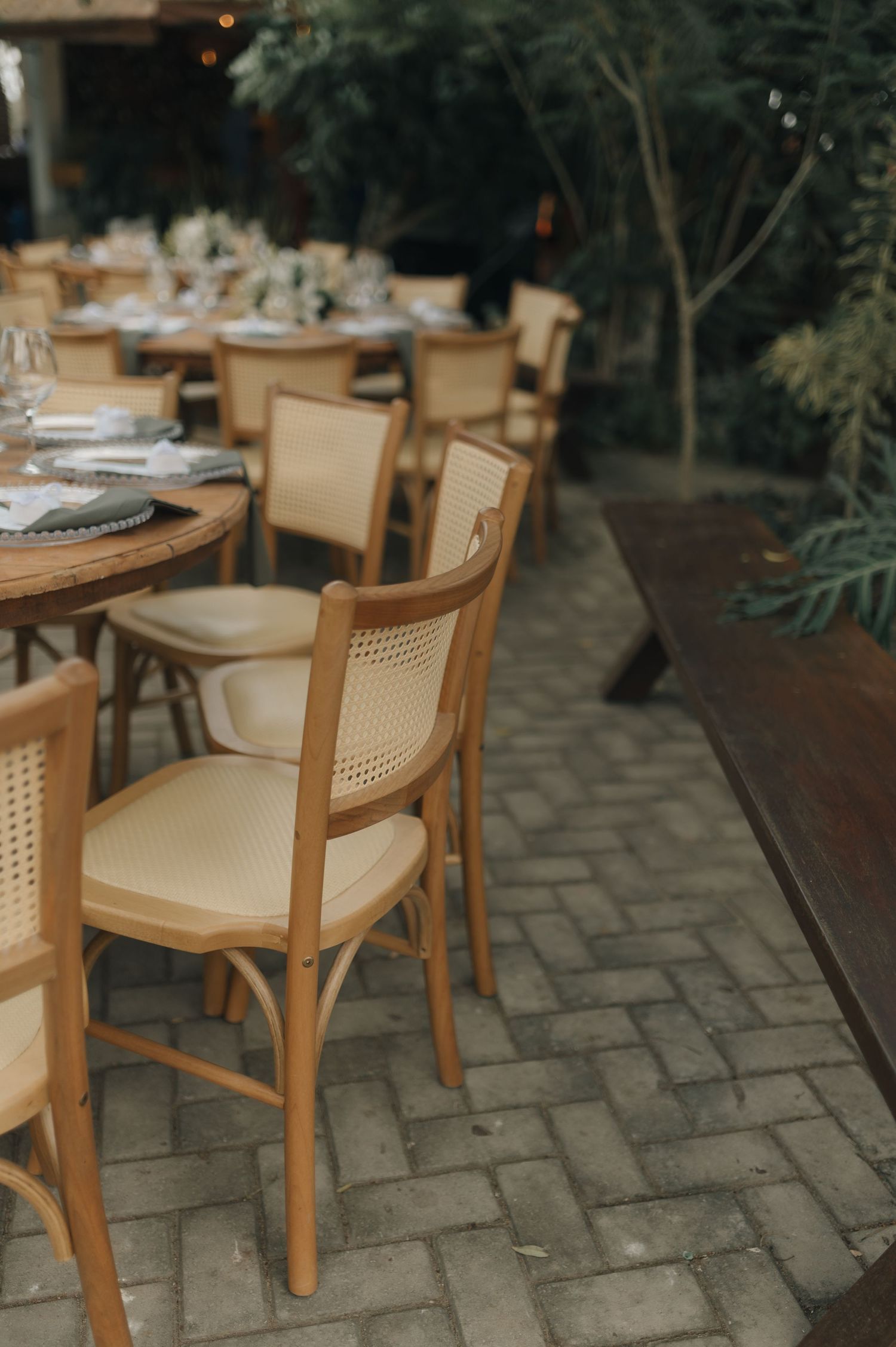 Elegant table settings with wooden chairs arranged at an outdoor dining venue.