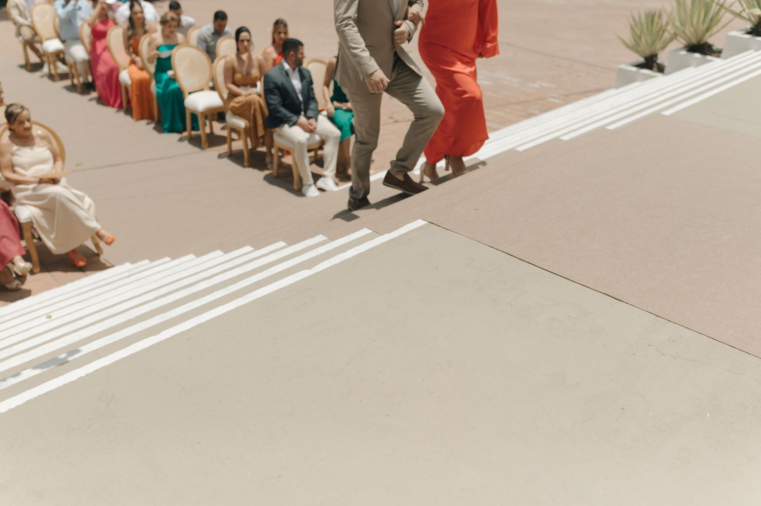 Aerial view of wedding attendees seated along white painted lines on concrete.