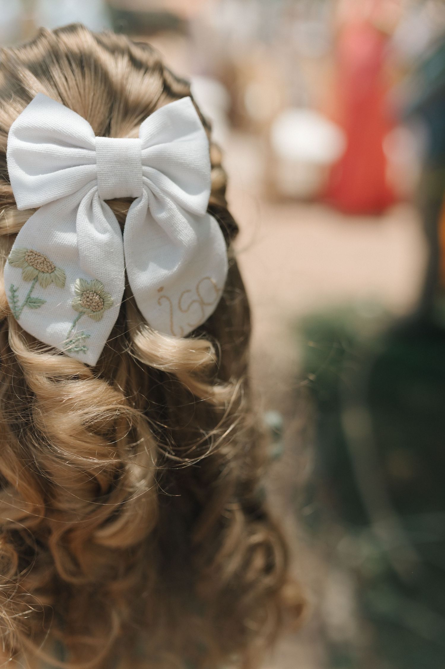 Close-up of elegant white bow hair accessory with curled blonde hair.