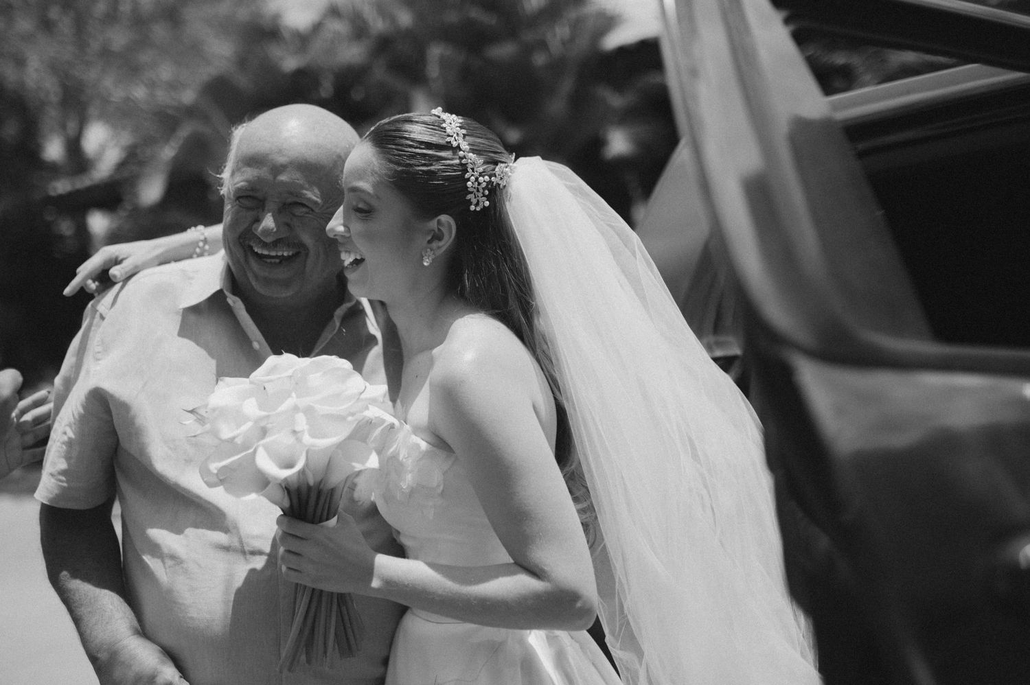 Black and white photo of joyful wedding moment with white bouquet.