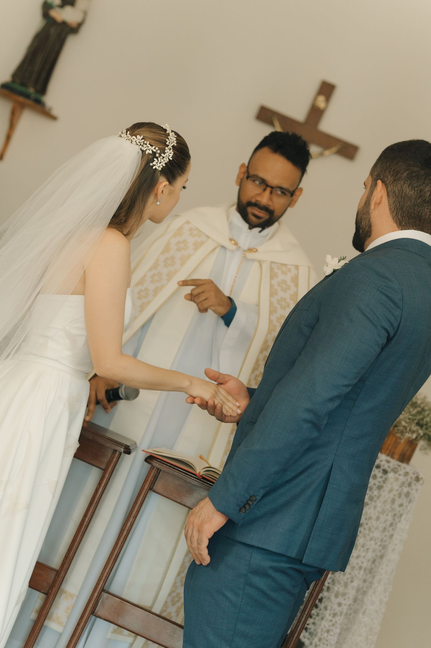 A traditional church wedding ceremony with the bride in white and groom in navy exchanging vows at the altar.