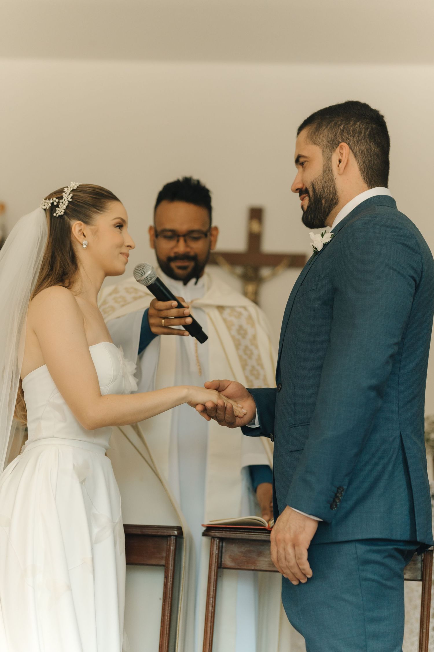 An intimate church wedding ceremony with the couple exchanging vows in front of a crucifix.