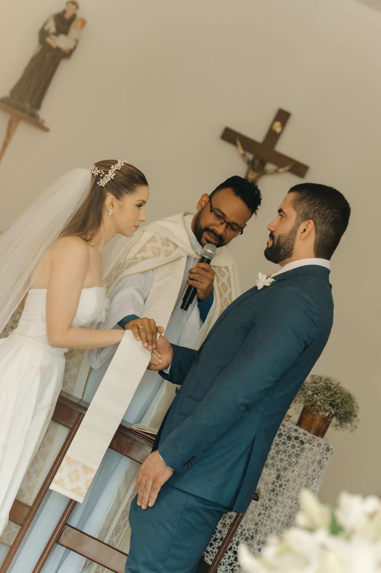 The exchange of wedding vows in a church with religious iconography visible in the background.