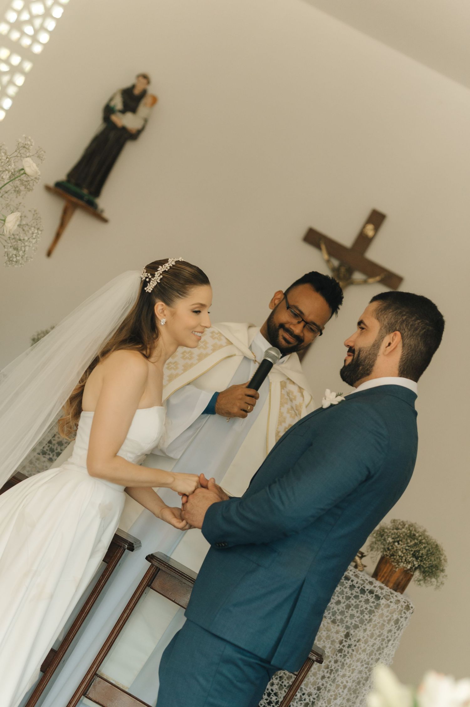 A sunlit church wedding ceremony showing the couple and officiant during their vows.