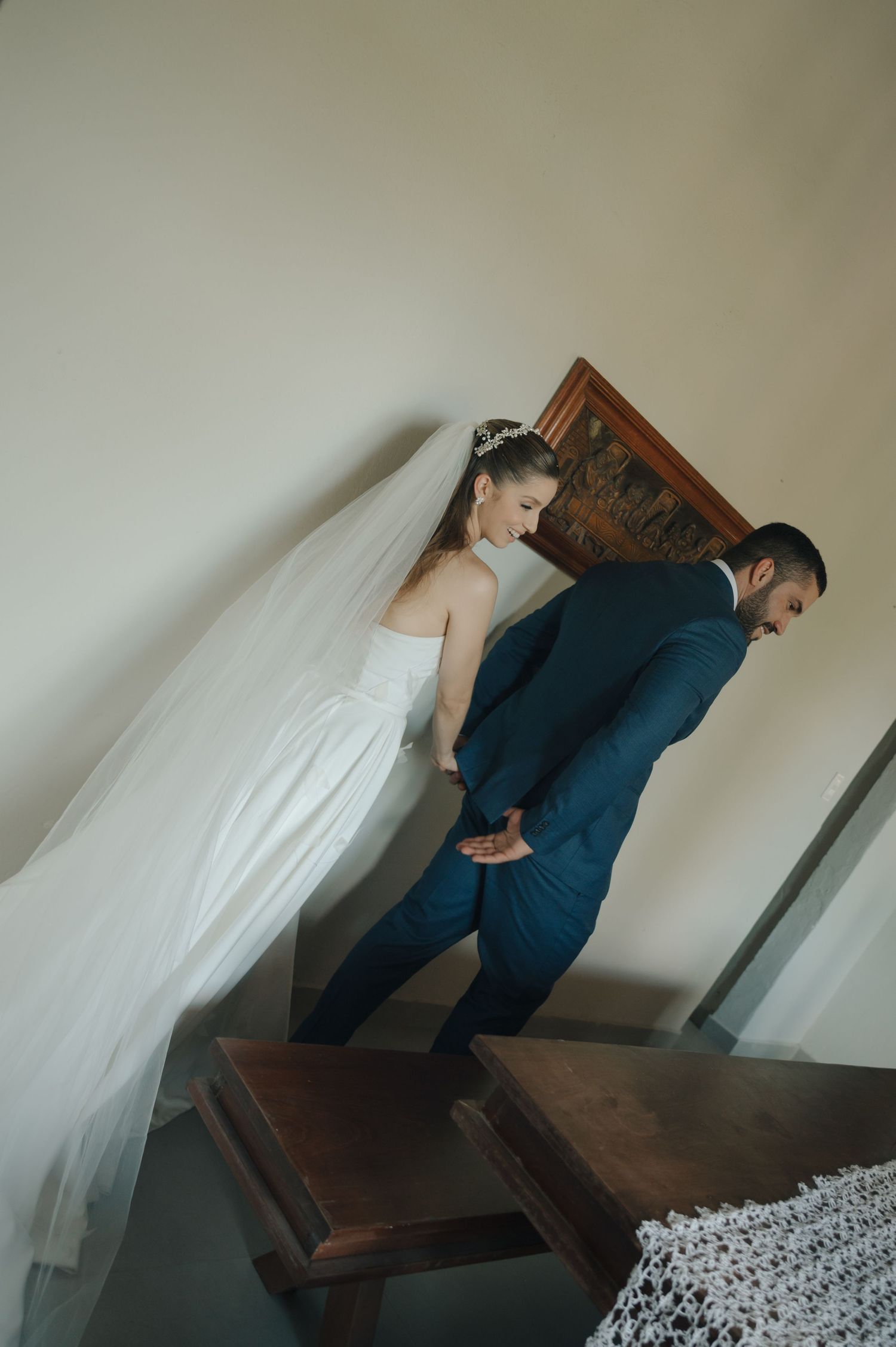 A candid wedding photo of a couple standing on wooden stairs in a vintage setting.