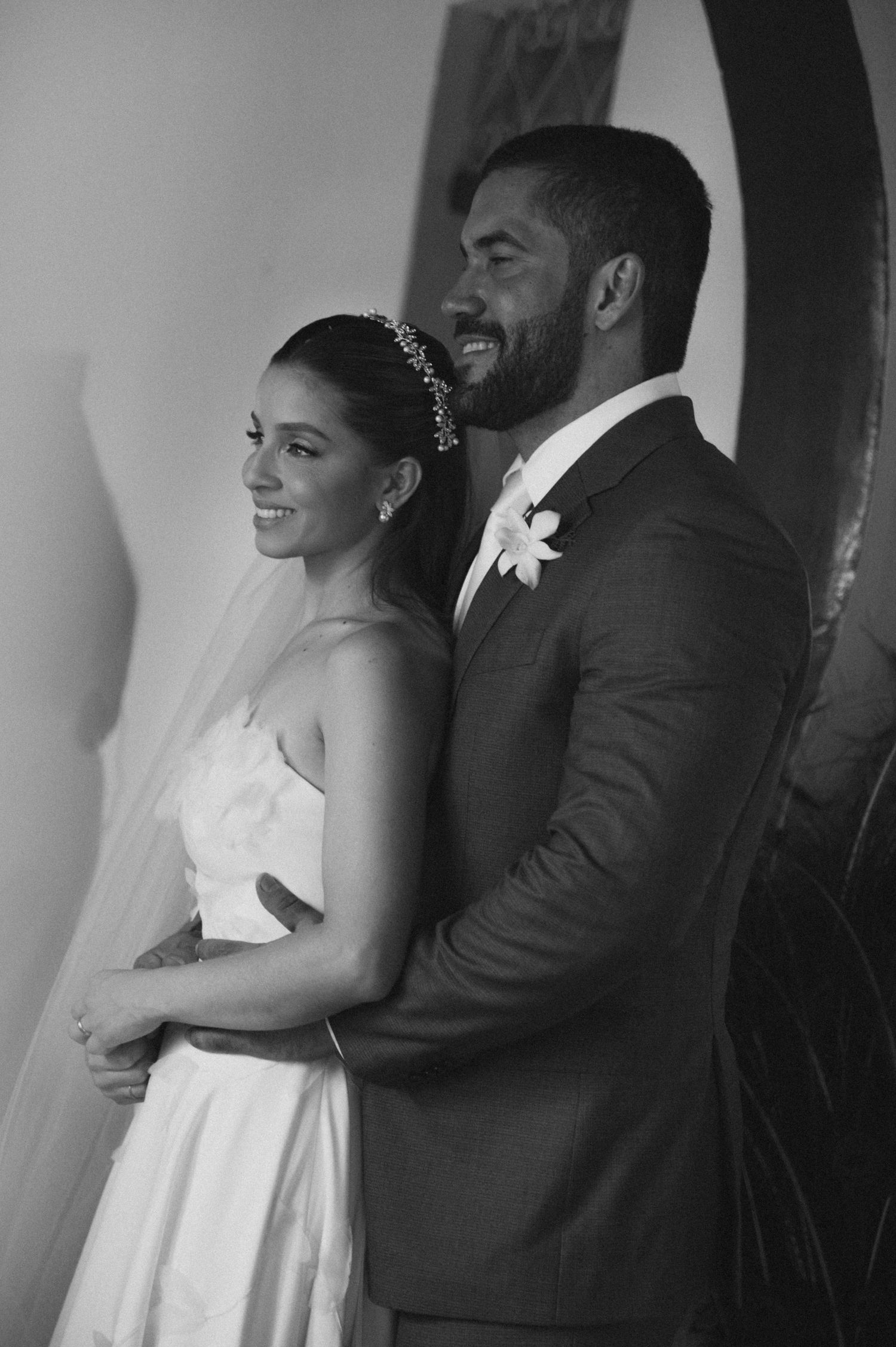 A black and white wedding portrait showing a joyful couple smiling in elegant attire.