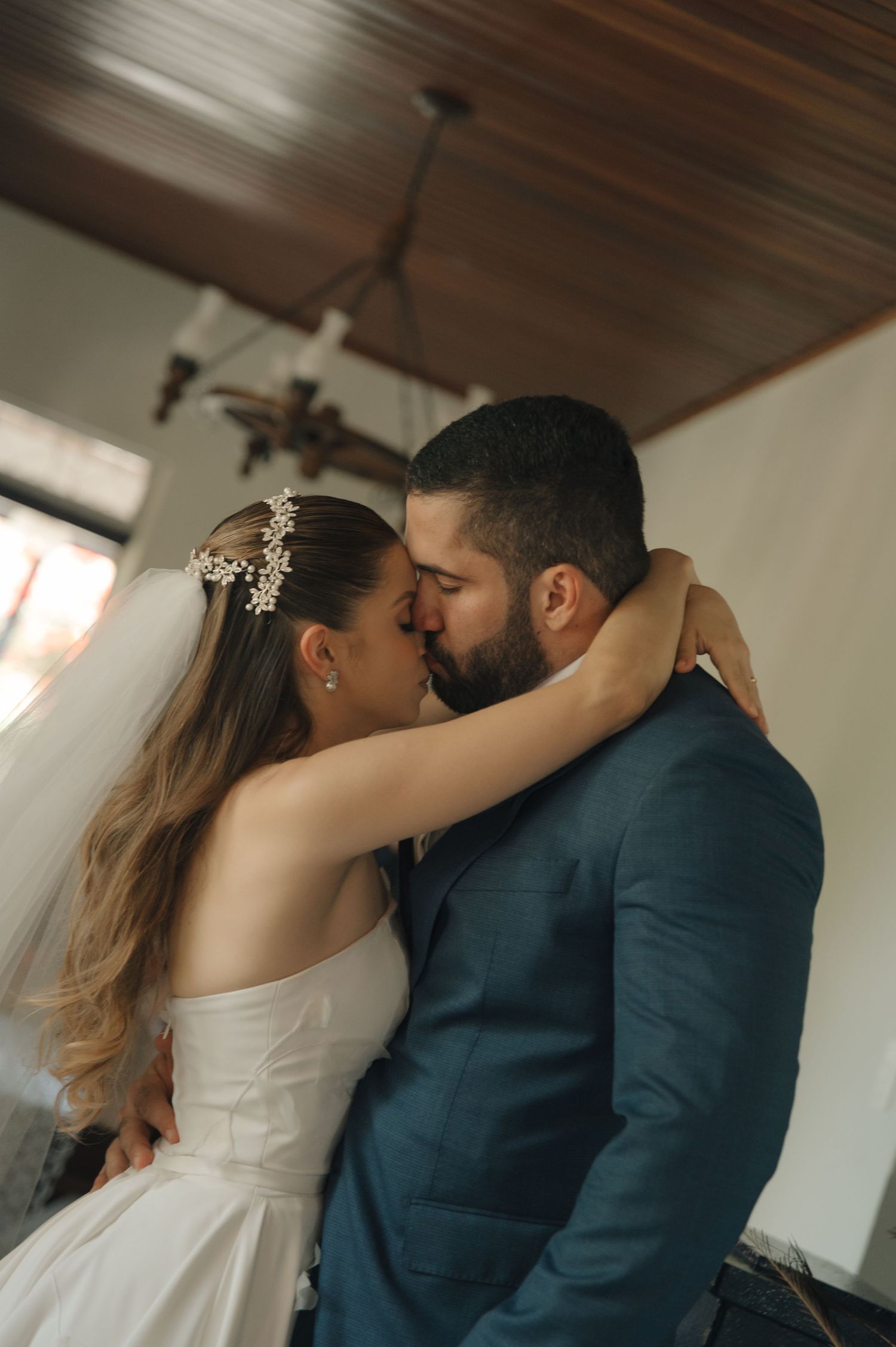 An intimate indoor wedding portrait showing a romantic embrace under wooden ceiling beams.