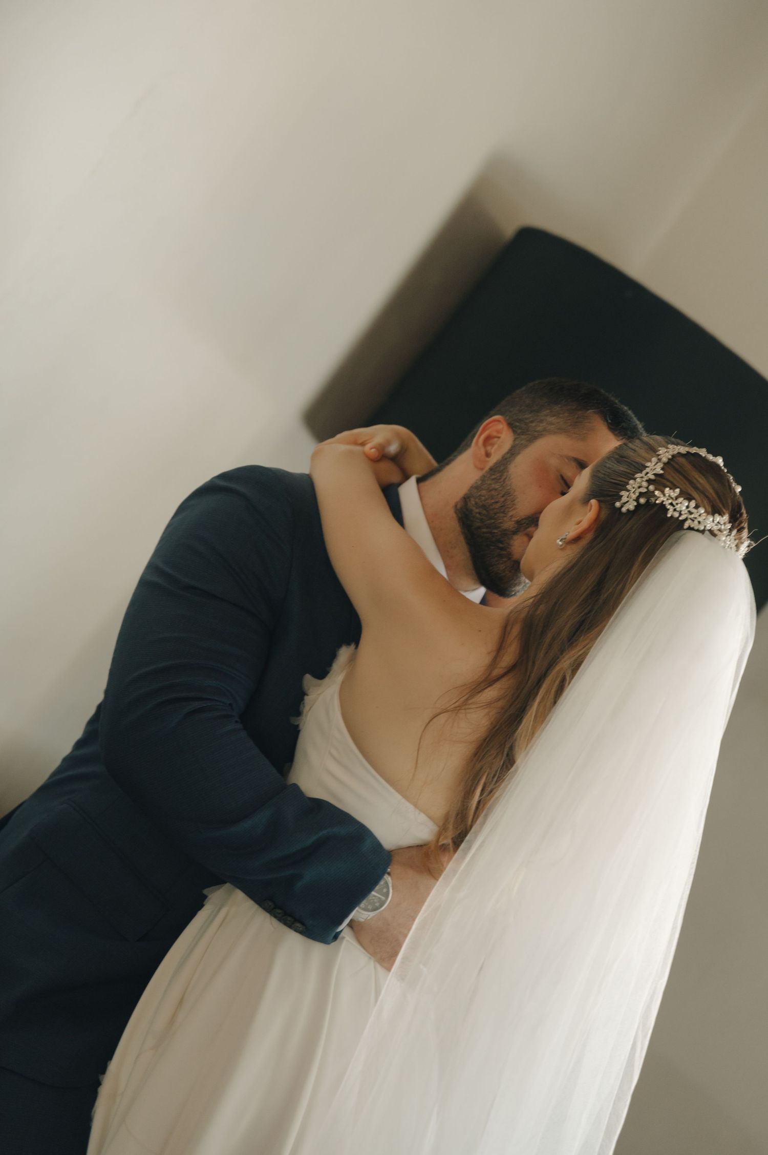A tender wedding moment captured against a minimalist white wall background.