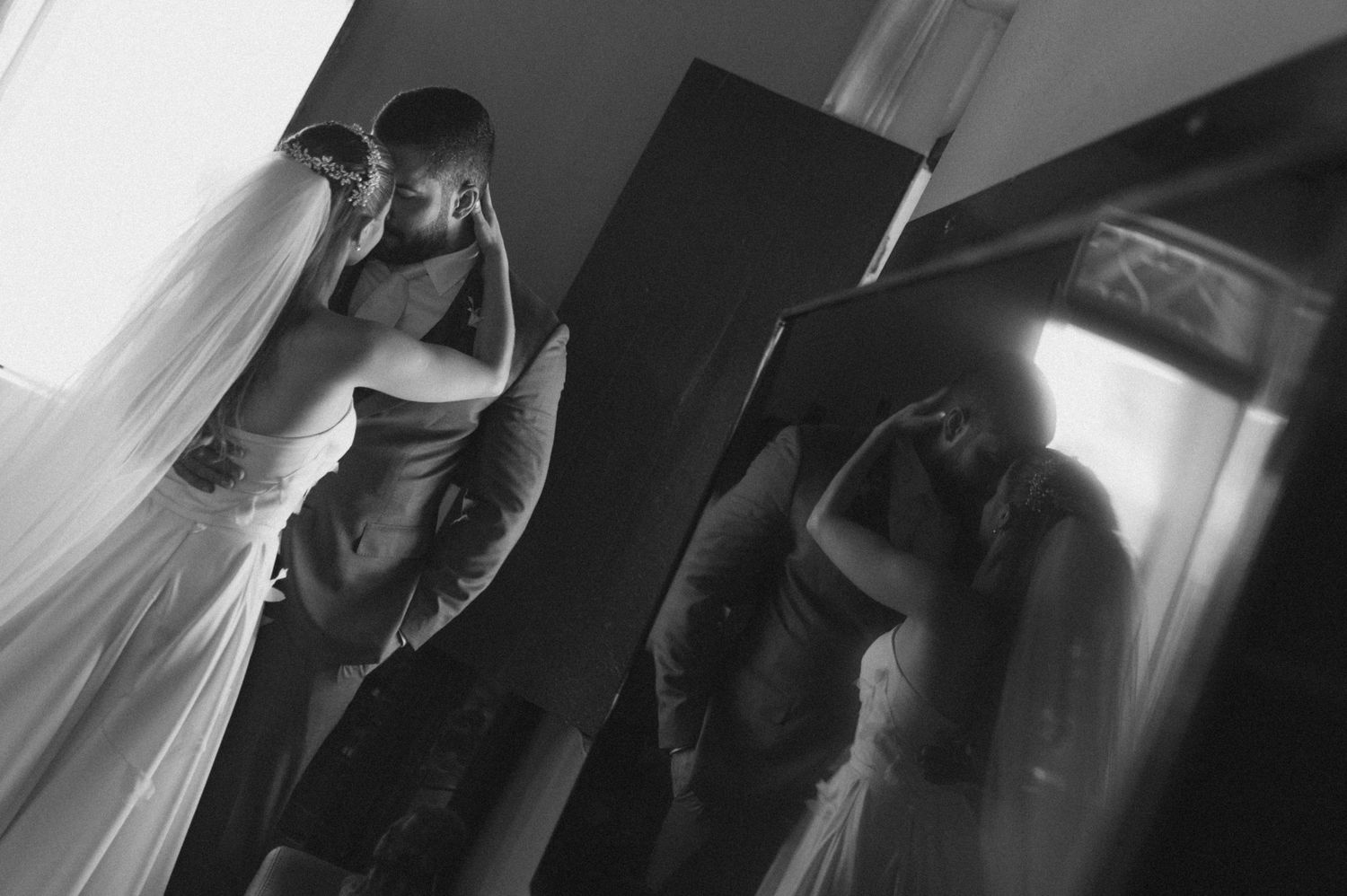 A dramatic black and white wedding photograph with reflections in a mirror.