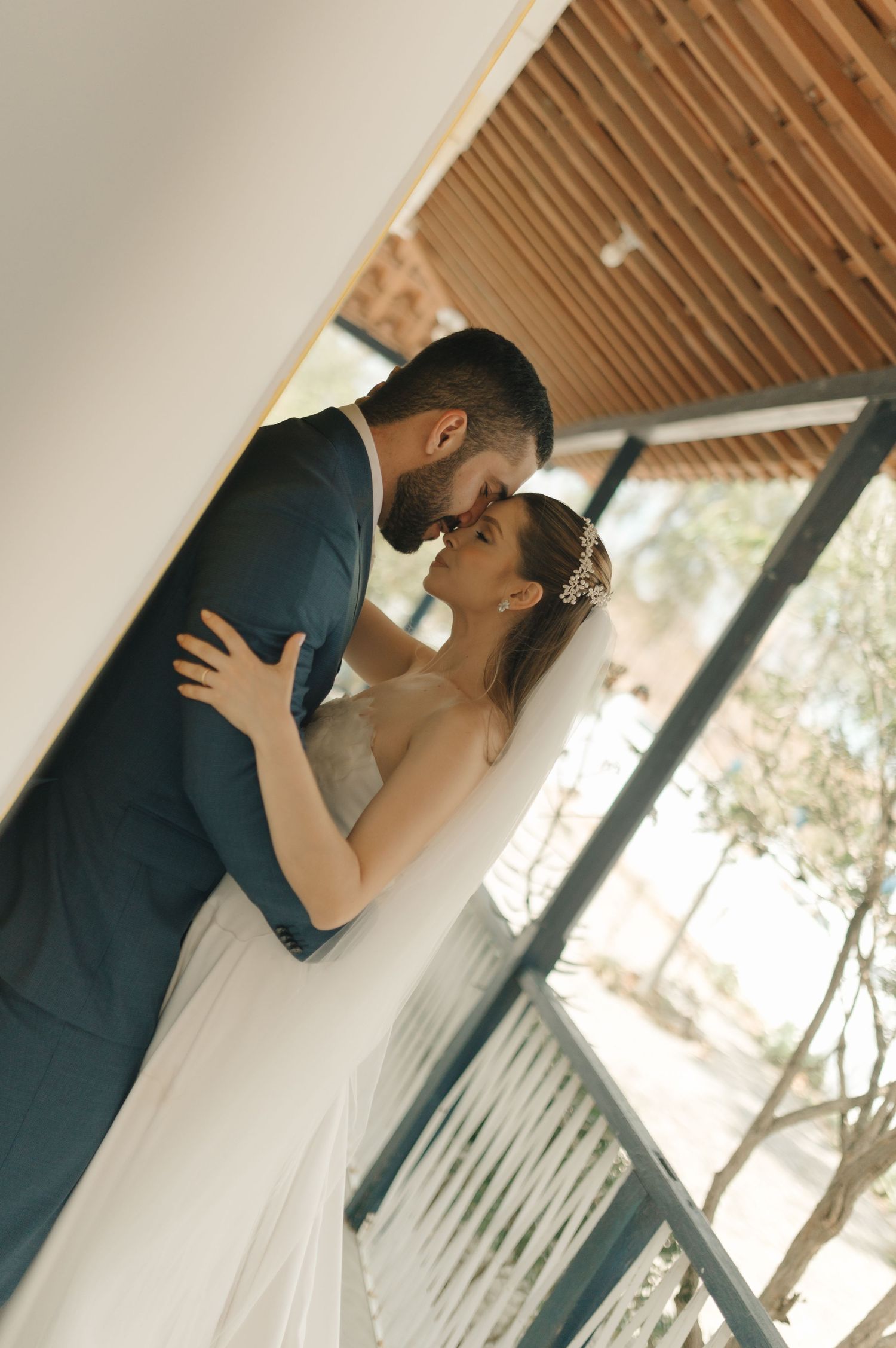 Candid moment of bride and groom sharing a close embrace under wooden beamed ceiling.