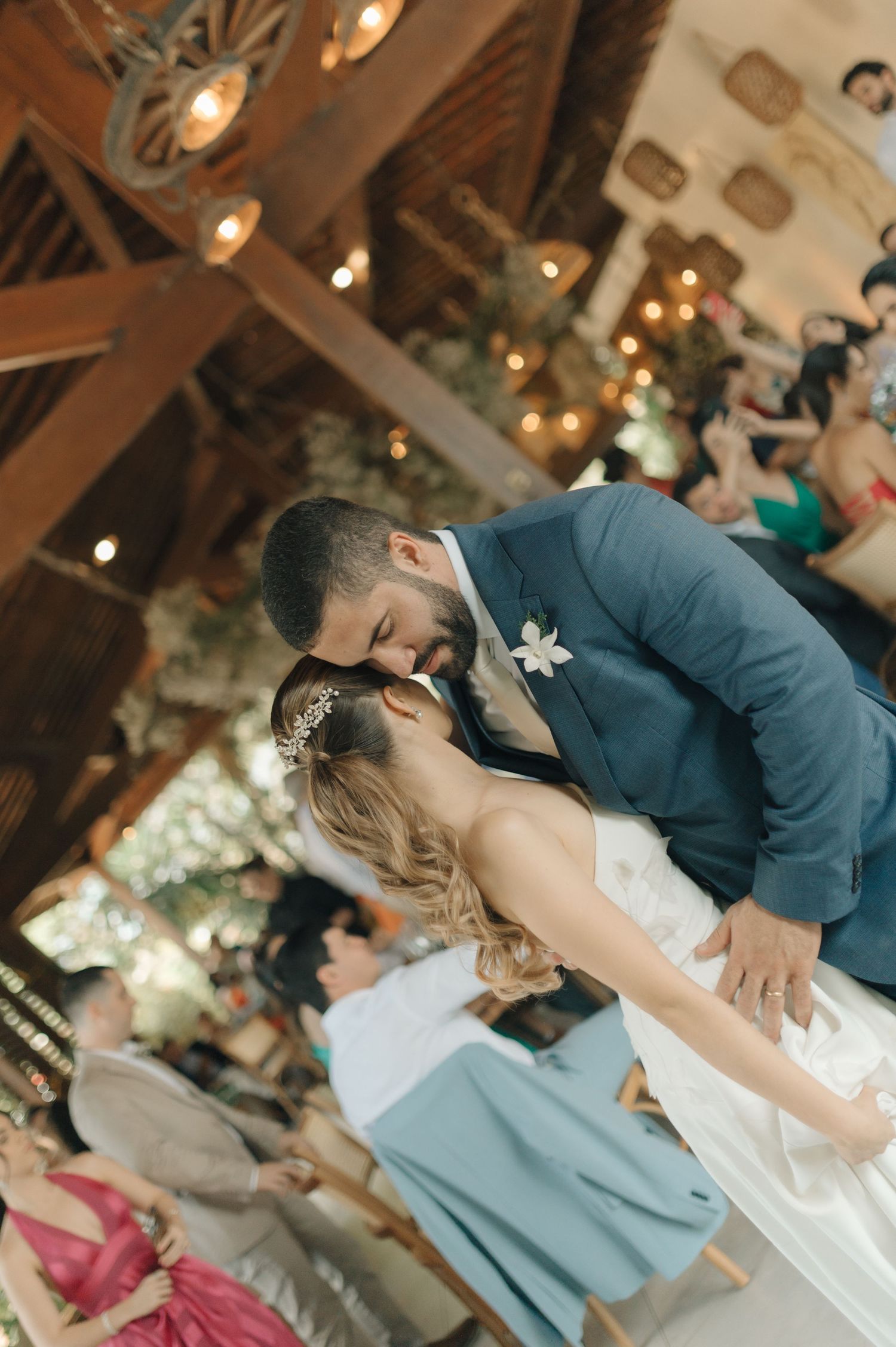 Couple sharing a romantic dance moment under rustic wooden beams at their wedding reception.
