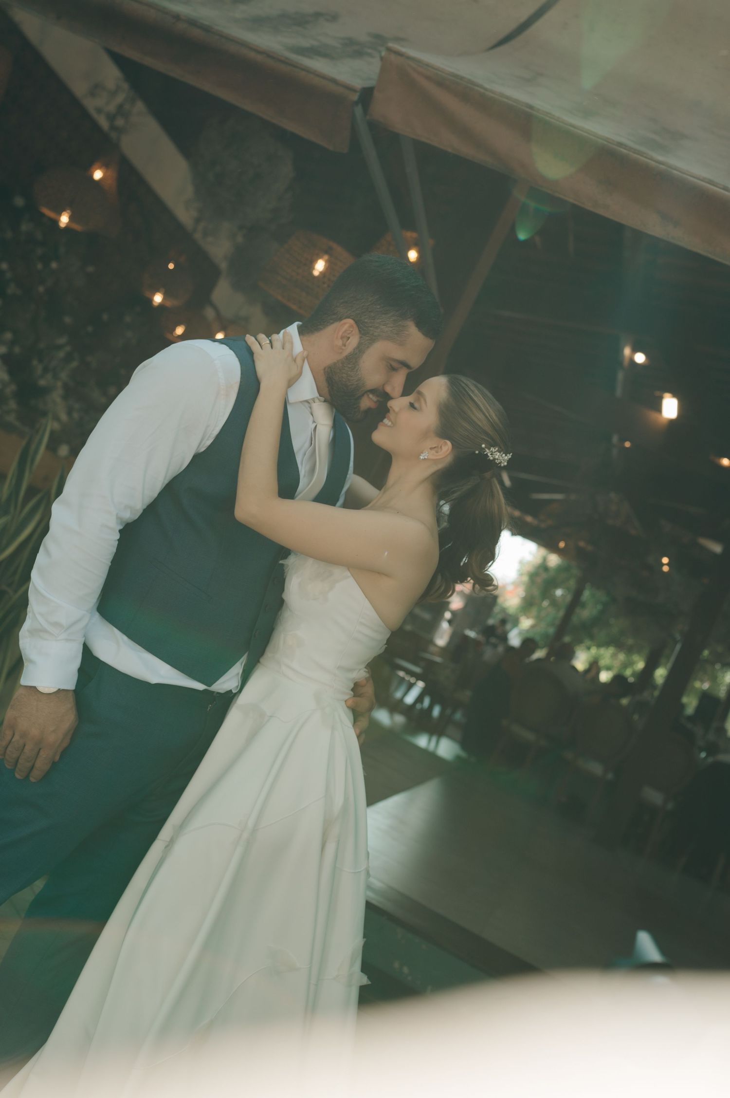 Romantic sunset dance moment between newlyweds under twinkling lights.