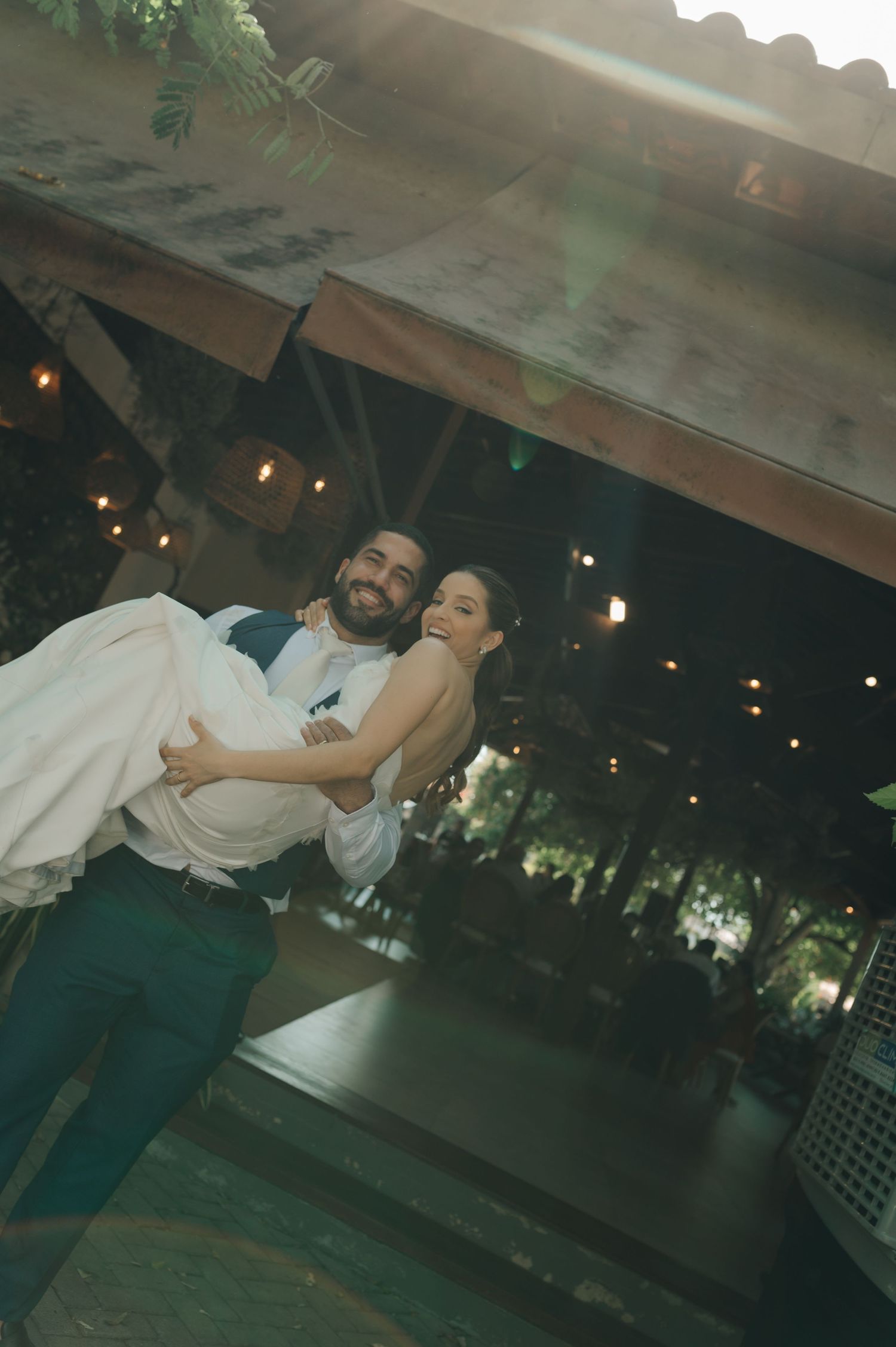Groom lifts bride playfully during evening wedding reception dance.