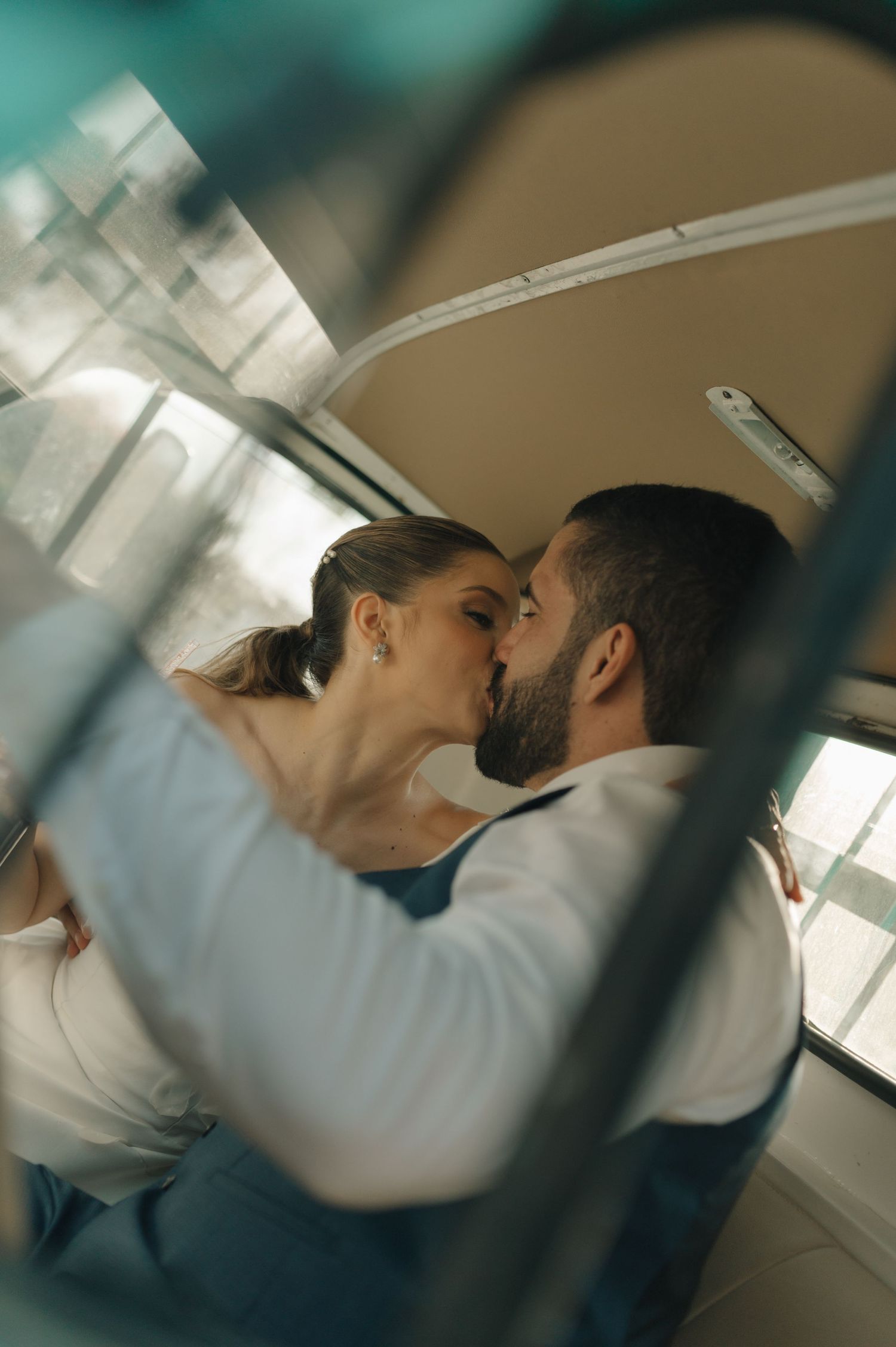 An intimate moment captured through a window reflection showing a couple in formal attire.