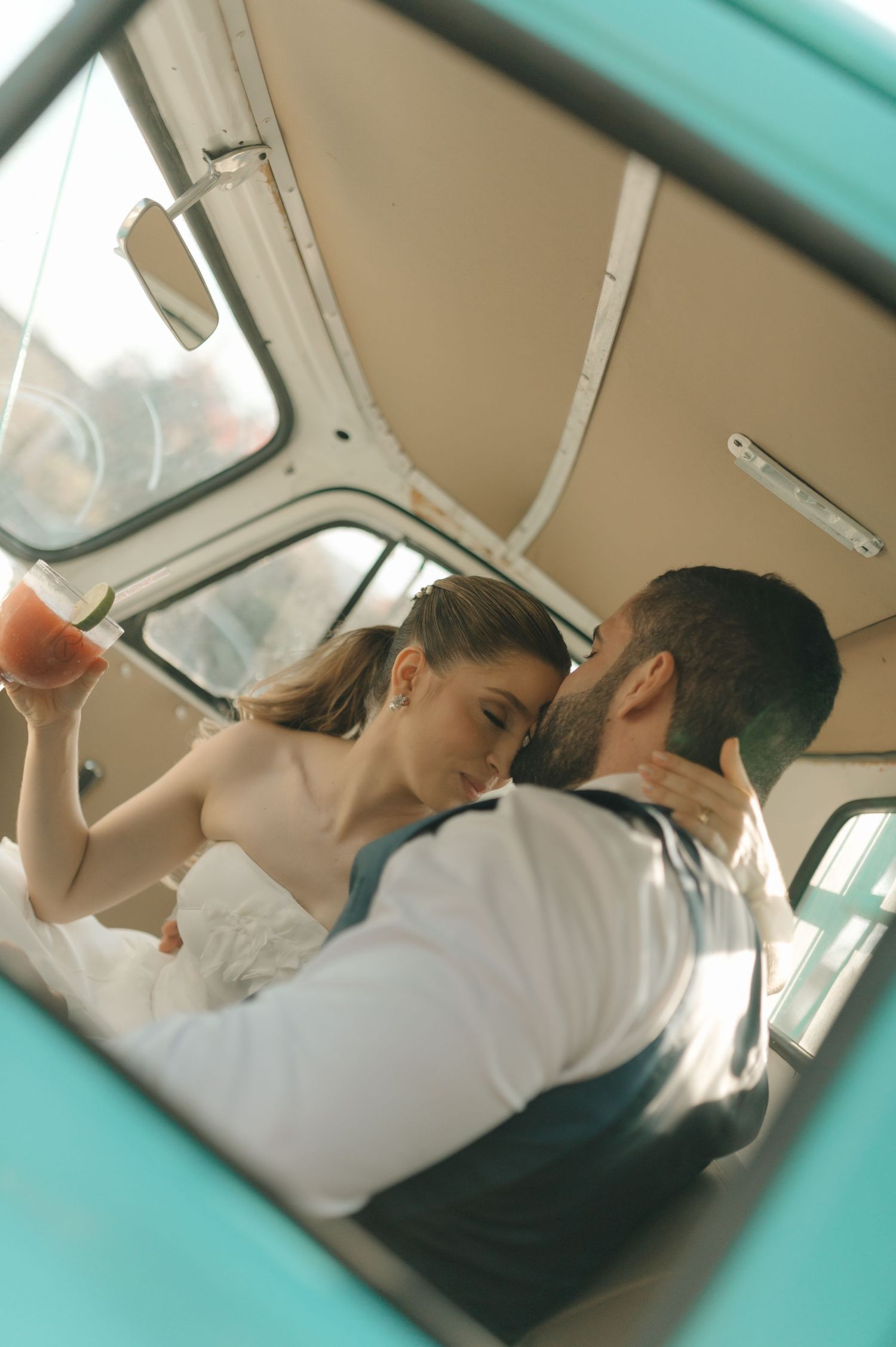 A romantic moment captured inside a classic car showing a couple in wedding attire.