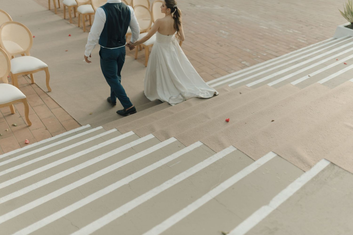 A couple walking up white stairs together during their wedding celebration.