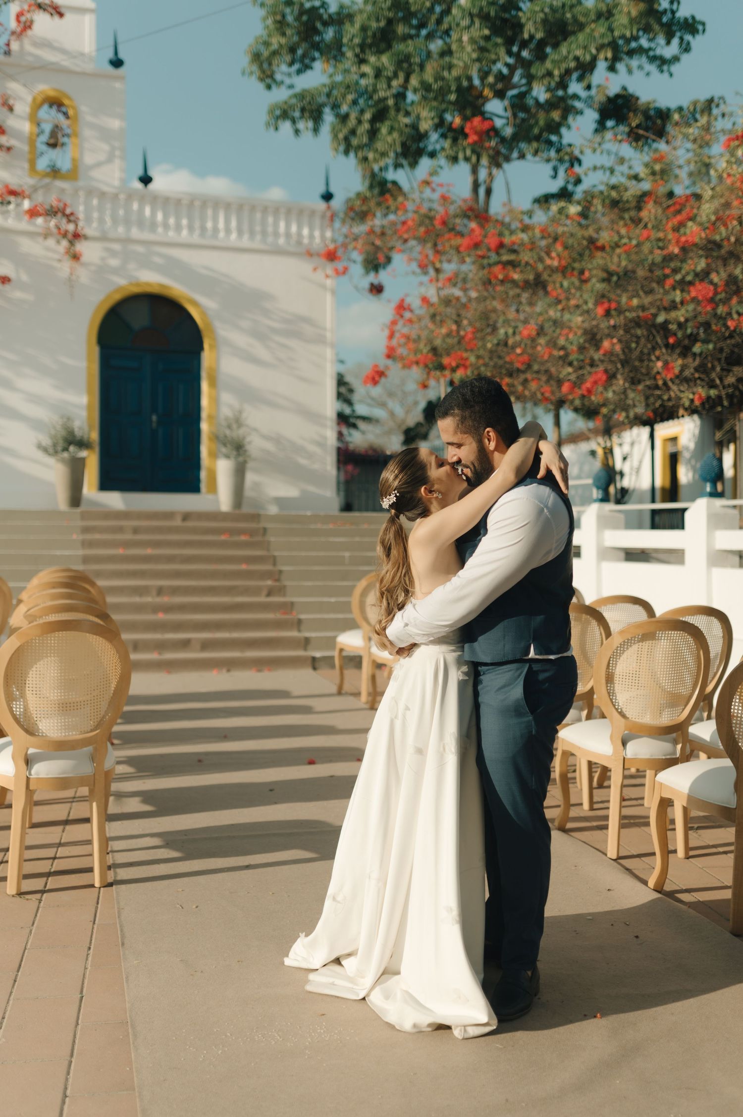 Couple sharing a romantic moment on outdoor steps with orange flowers in the background.