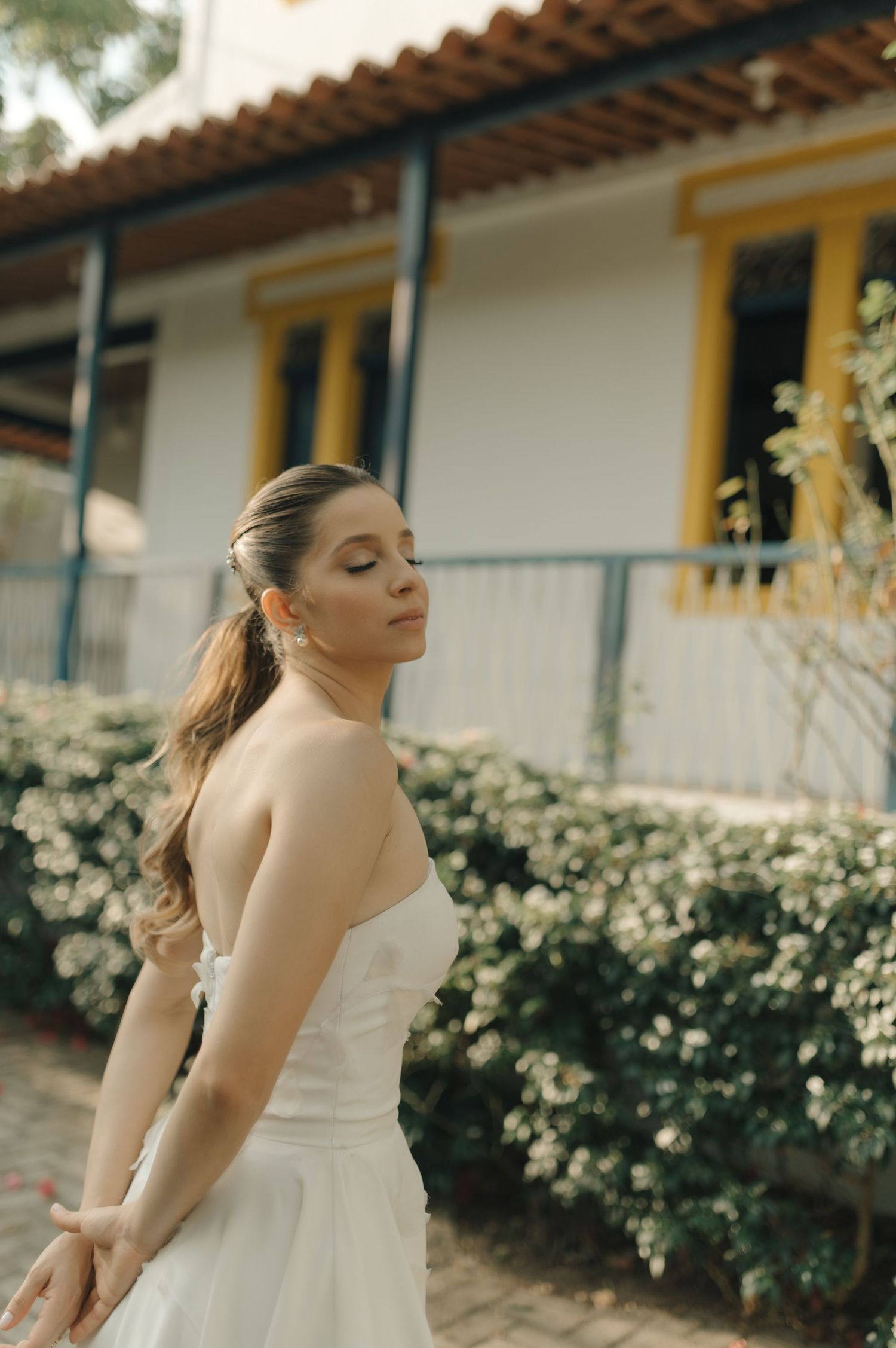Side profile of a bride in a simple white dress against a garden backdrop.