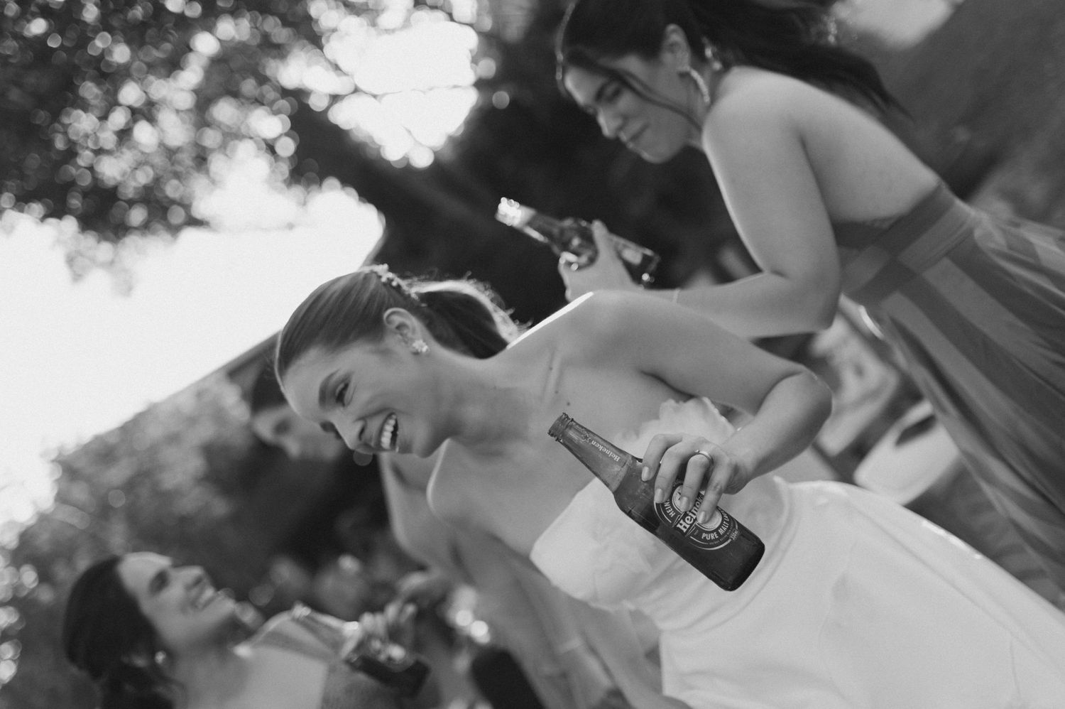Guests enjoying drinks and laughter at an outdoor wedding celebration.