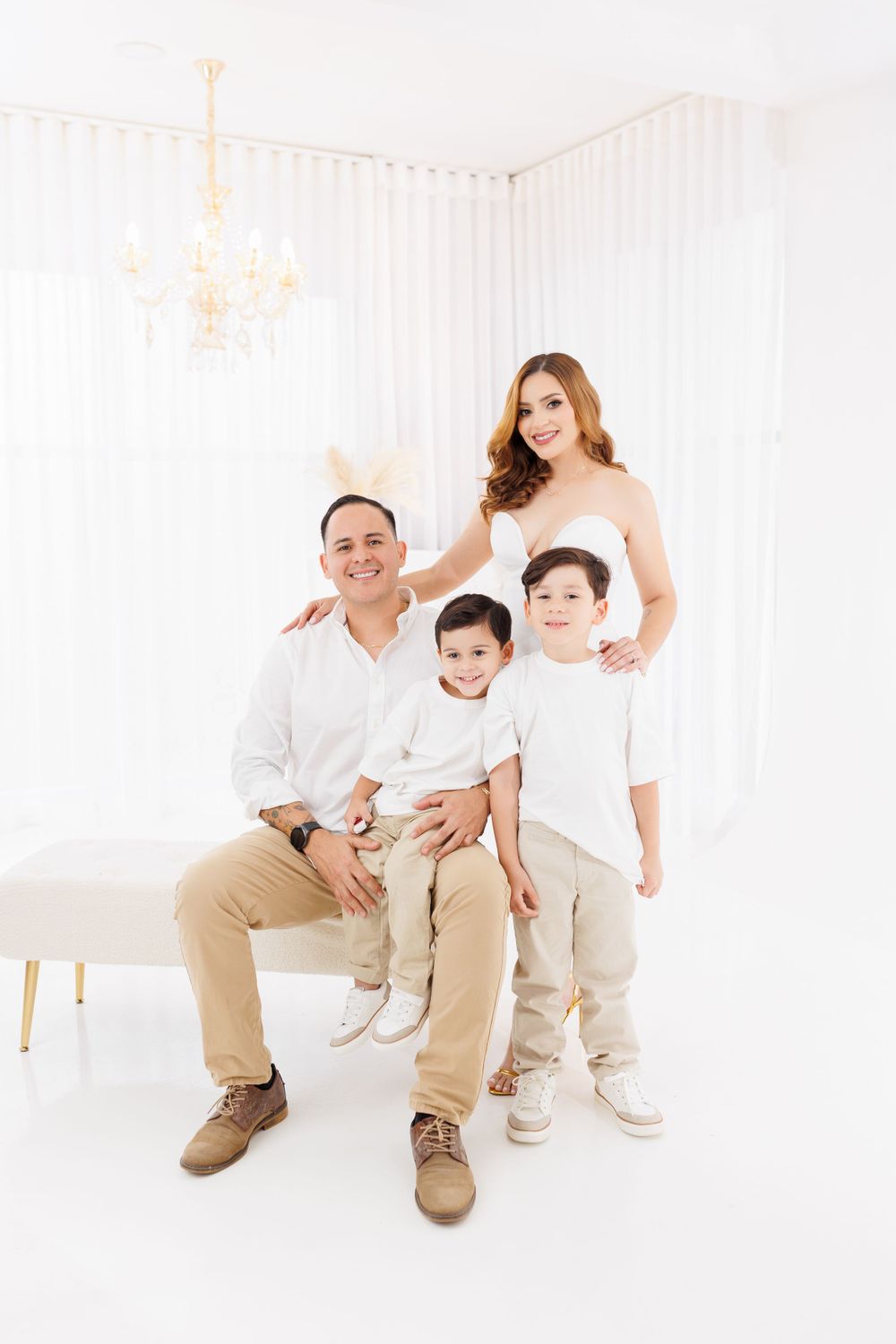 Candid family photo with parents and children in coordinated white and beige outfits.