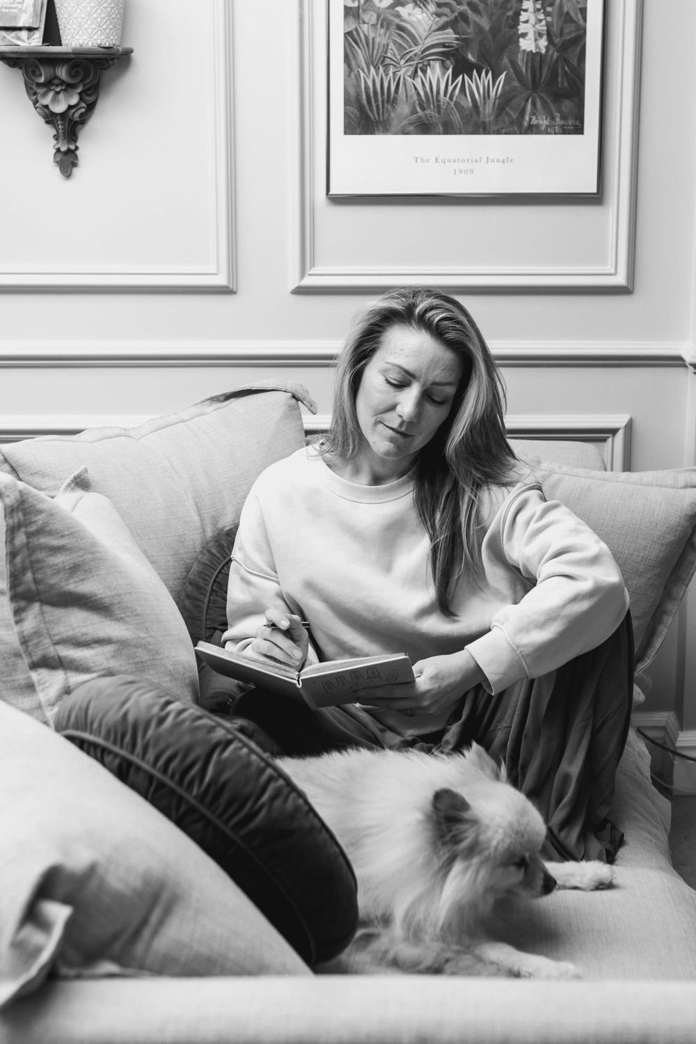 personal branding shoot of a portrait of a therapist sat on a couch reading a book with her dog at her feet