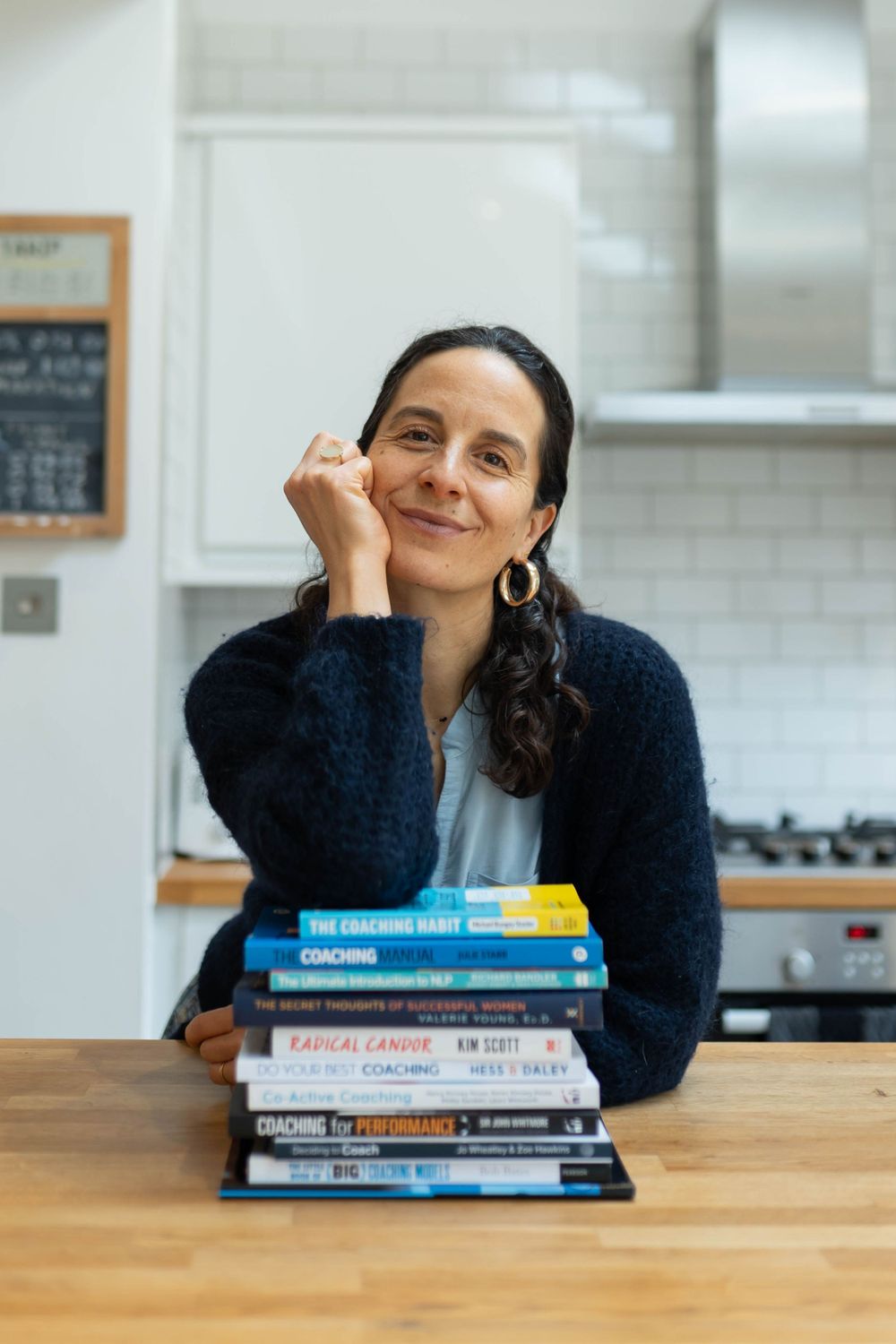 confidence coach leans in her kitchen smiling and holding a cup of tea in her personal branding shoot brighton